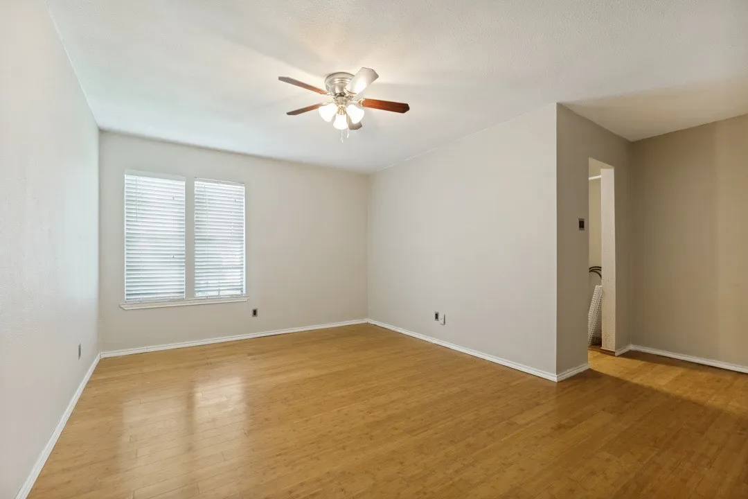 Bright interior space featuring wood-finish flooring, neutral-toned walls, and a ceiling fan with integrated lighting