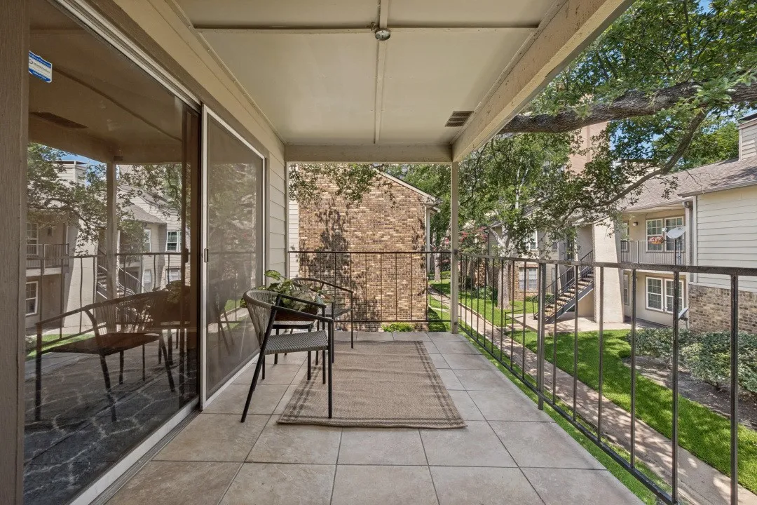 Covered balcony featuring tile flooring and black metal railing