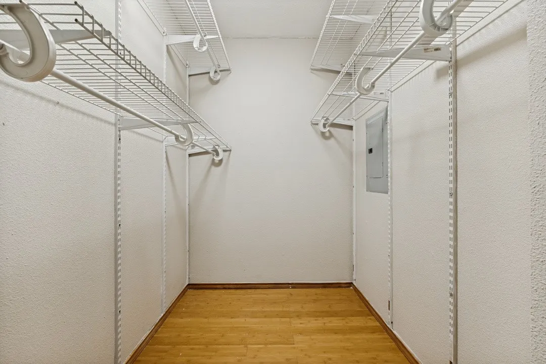 Walk-in closet featuring light wood-finish flooring, white wire shelving, and hanging rods