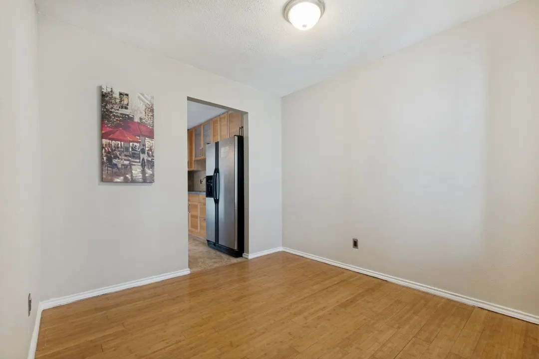 Well-lit interior space featuring wood-finish flooring, white baseboards, and neutral wall paint