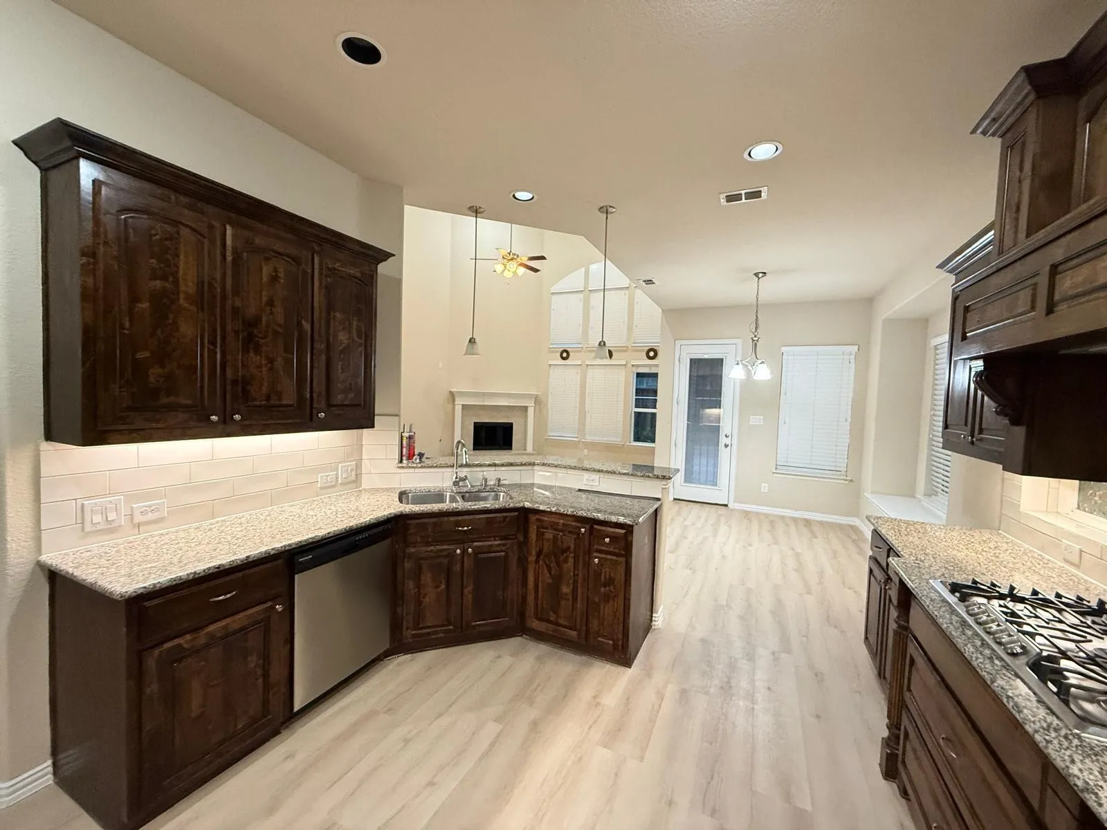 Kitchen featuring dark wood cabinetry, light-toned wood-finish flooring, and light granite countertops