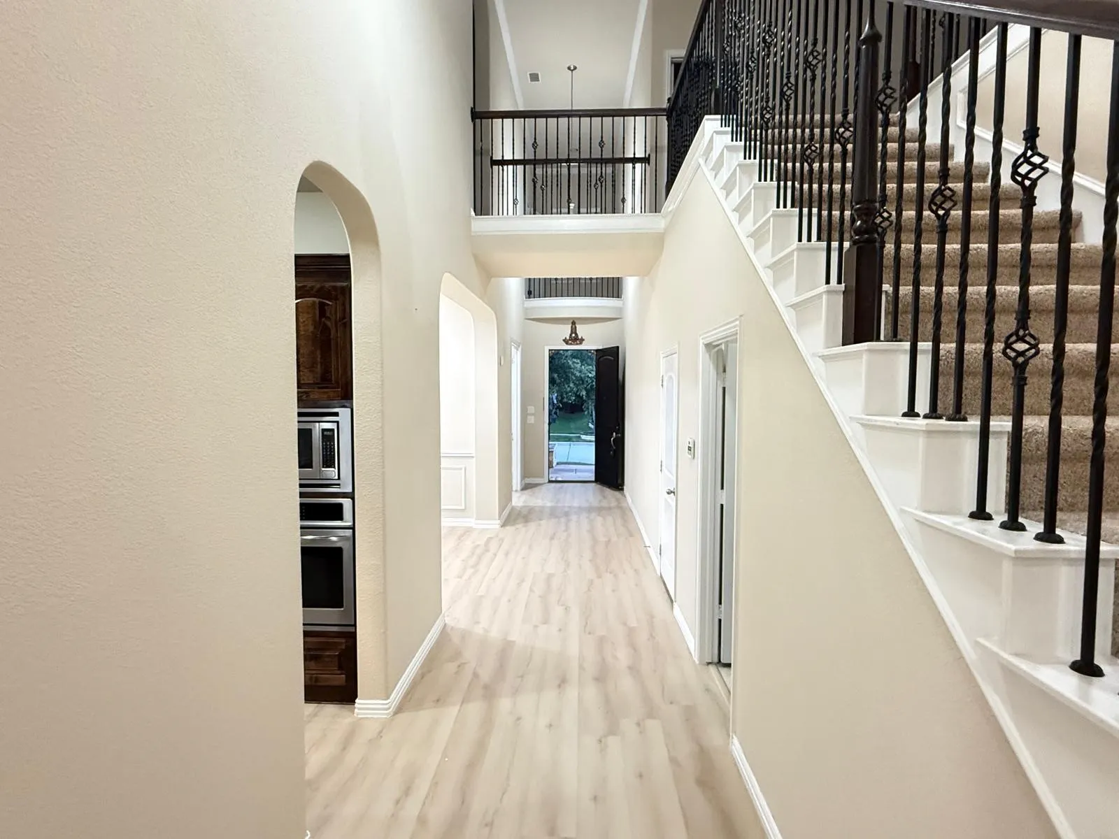 Open foyer with light wood-finish flooring and a two-story ceiling