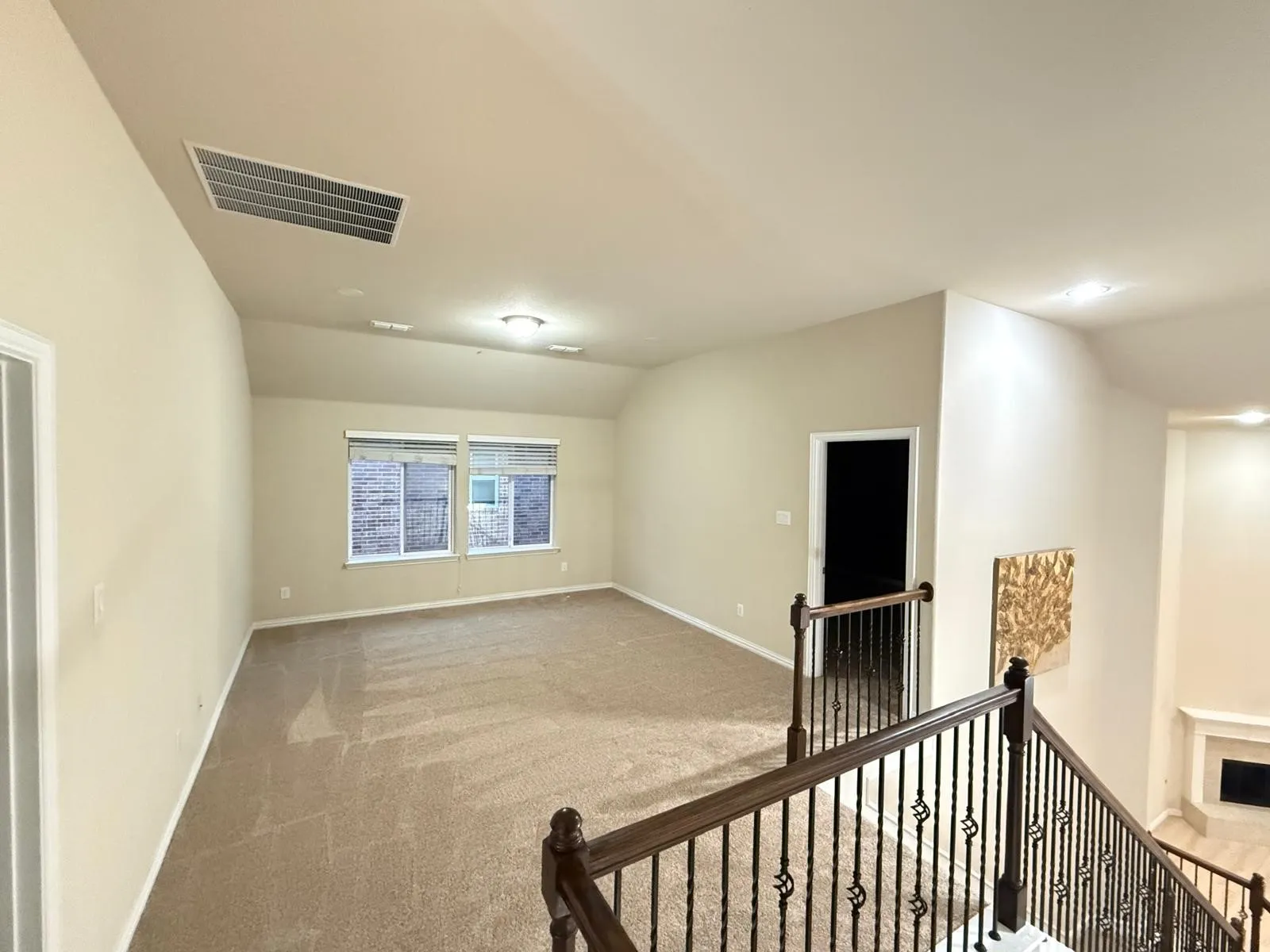 Spacious upper-level room with vaulted ceiling and carpeted flooring