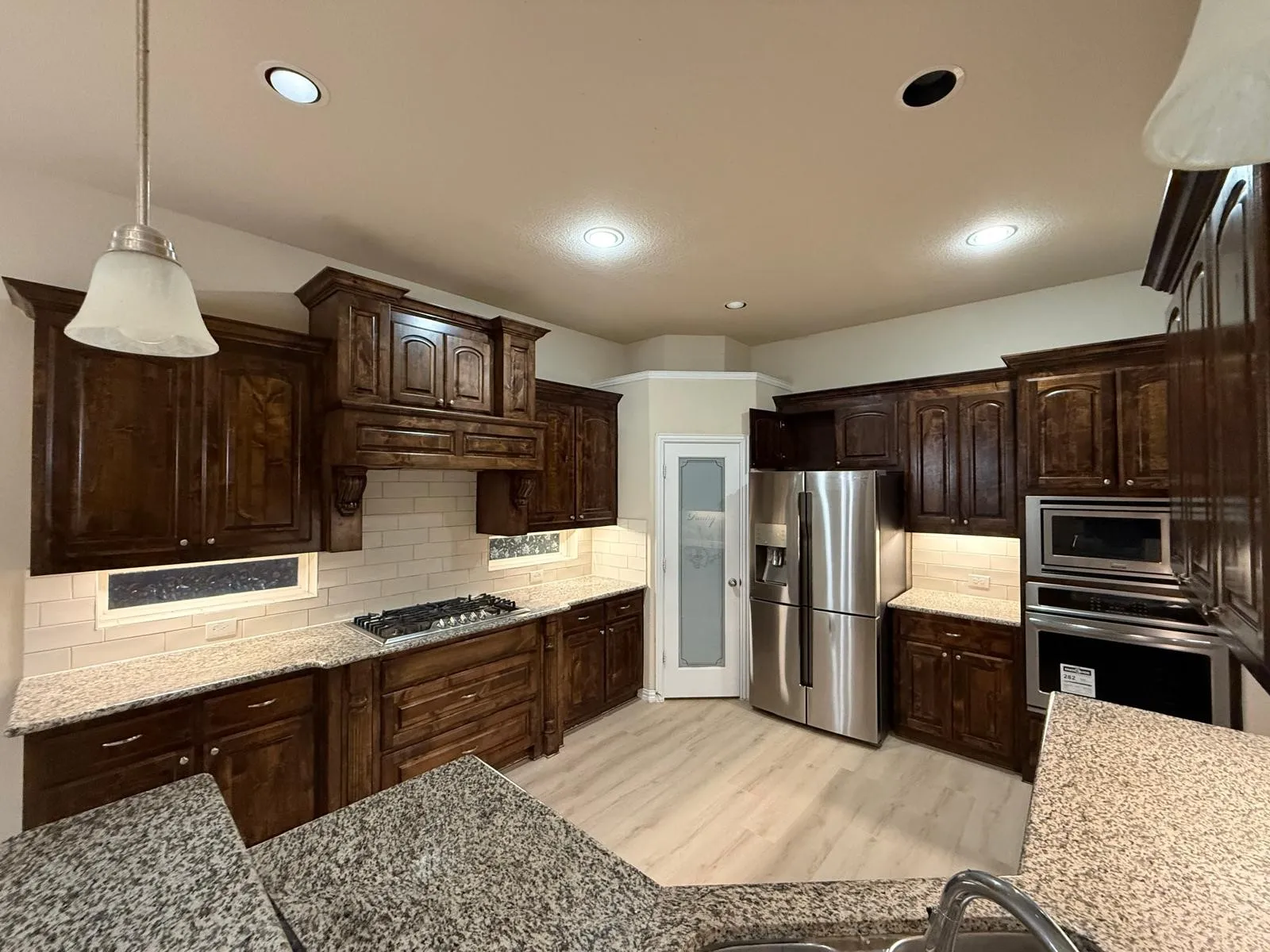 Kitchen featuring rich wood cabinetry, granite countertops, a tiled backsplash, and stainless steel appliances