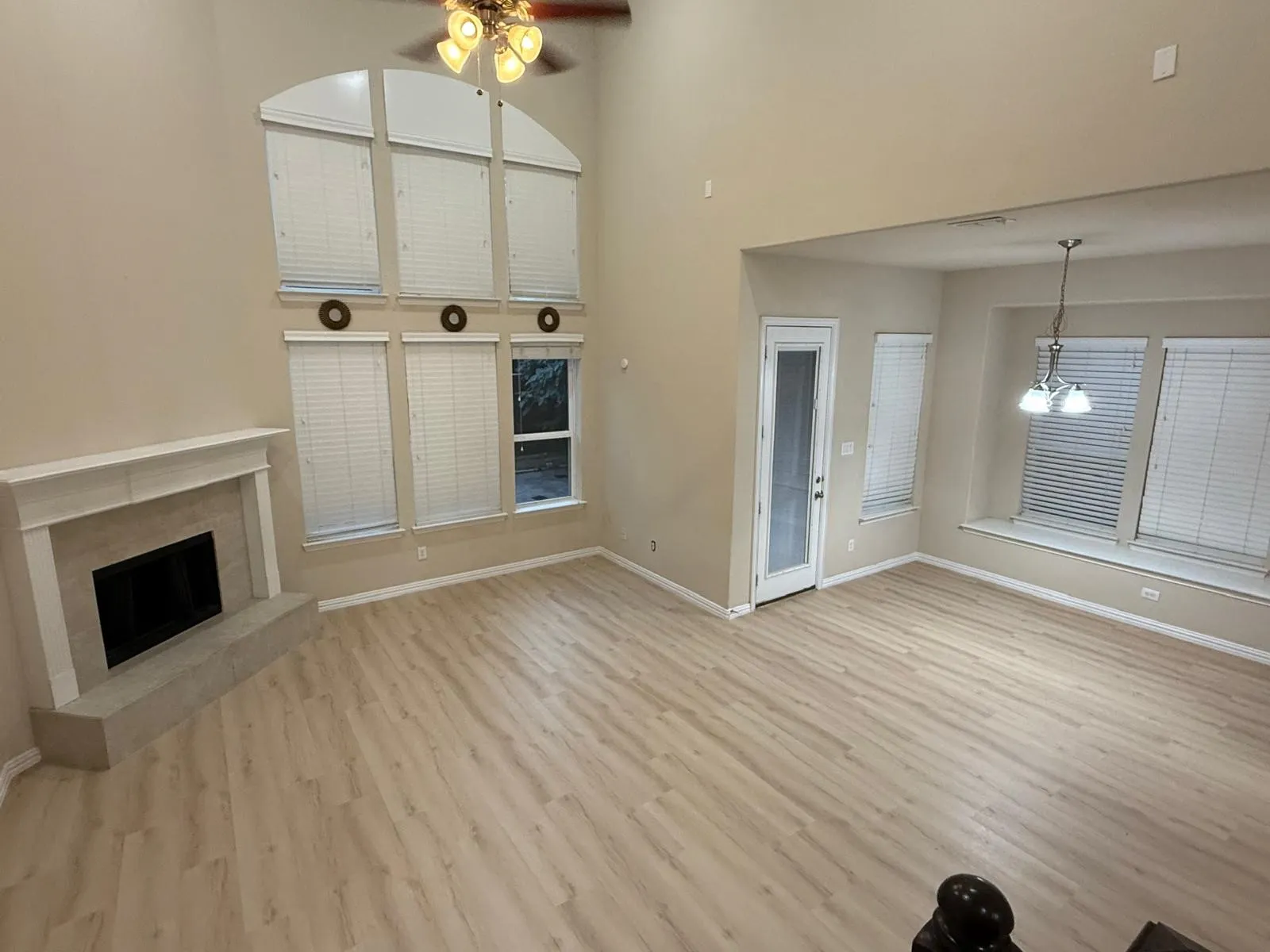 Spacious room with a vaulted ceiling, wood-finish flooring, and a fireplace with a stone hearth