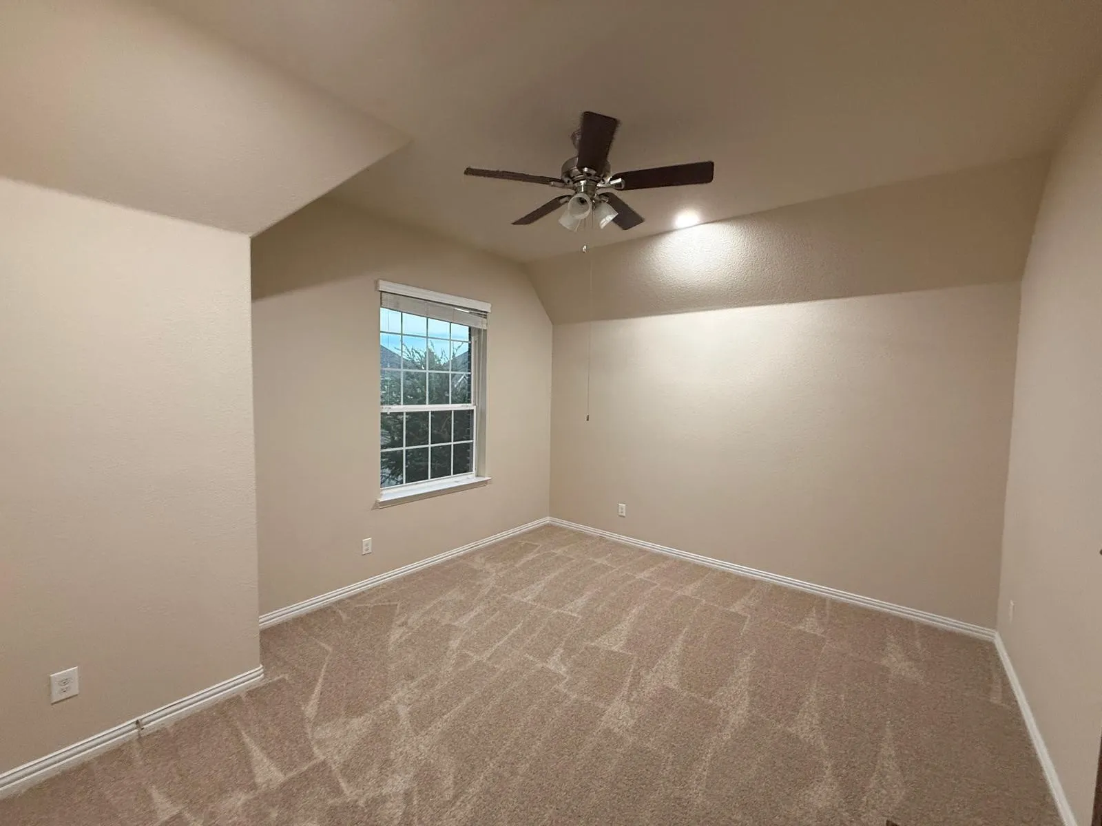 Carpeted room featuring neutral-toned walls, a window with blinds, and an overhead ceiling fan with integrated lighting