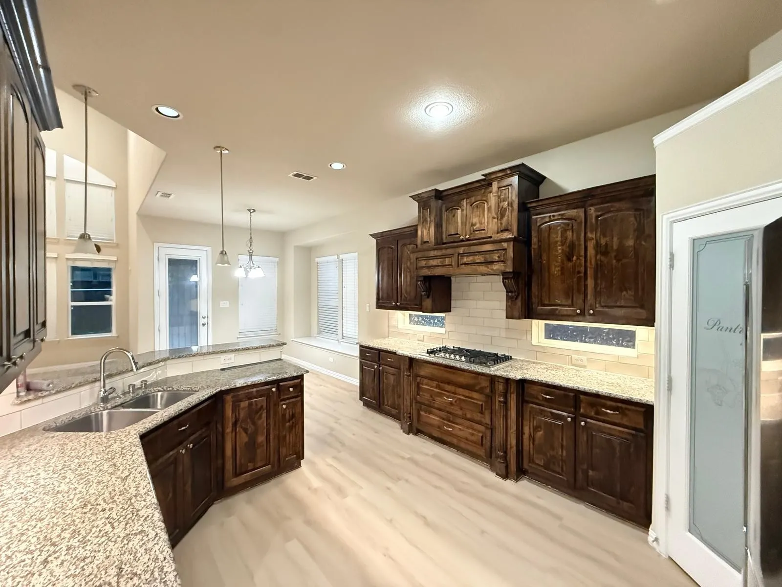 Kitchen featuring dark wood cabinetry, granite countertops, and light wood-finish flooring