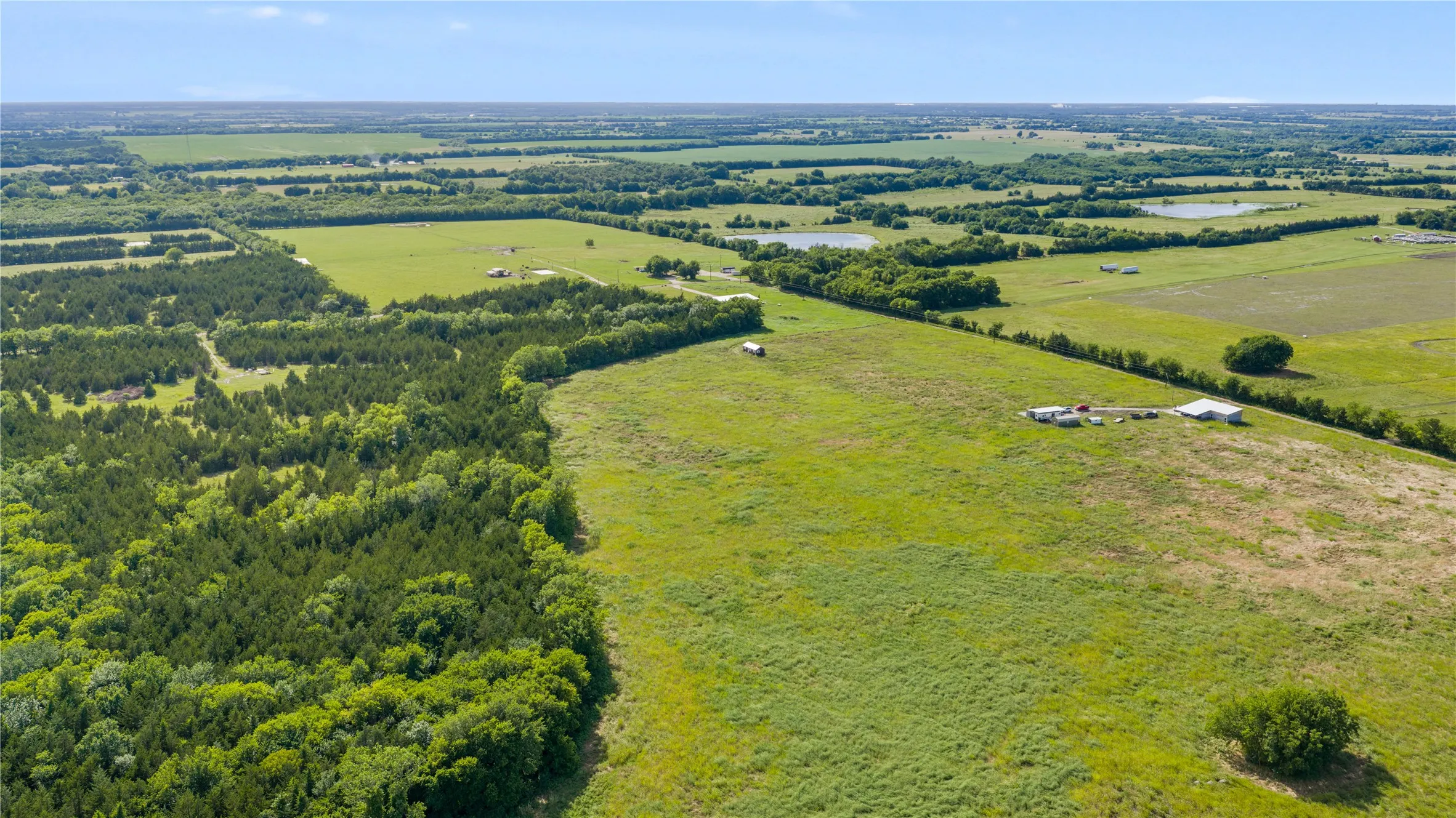 Expansive undeveloped land featuring a mix of open grassy fields and dense tree coverage