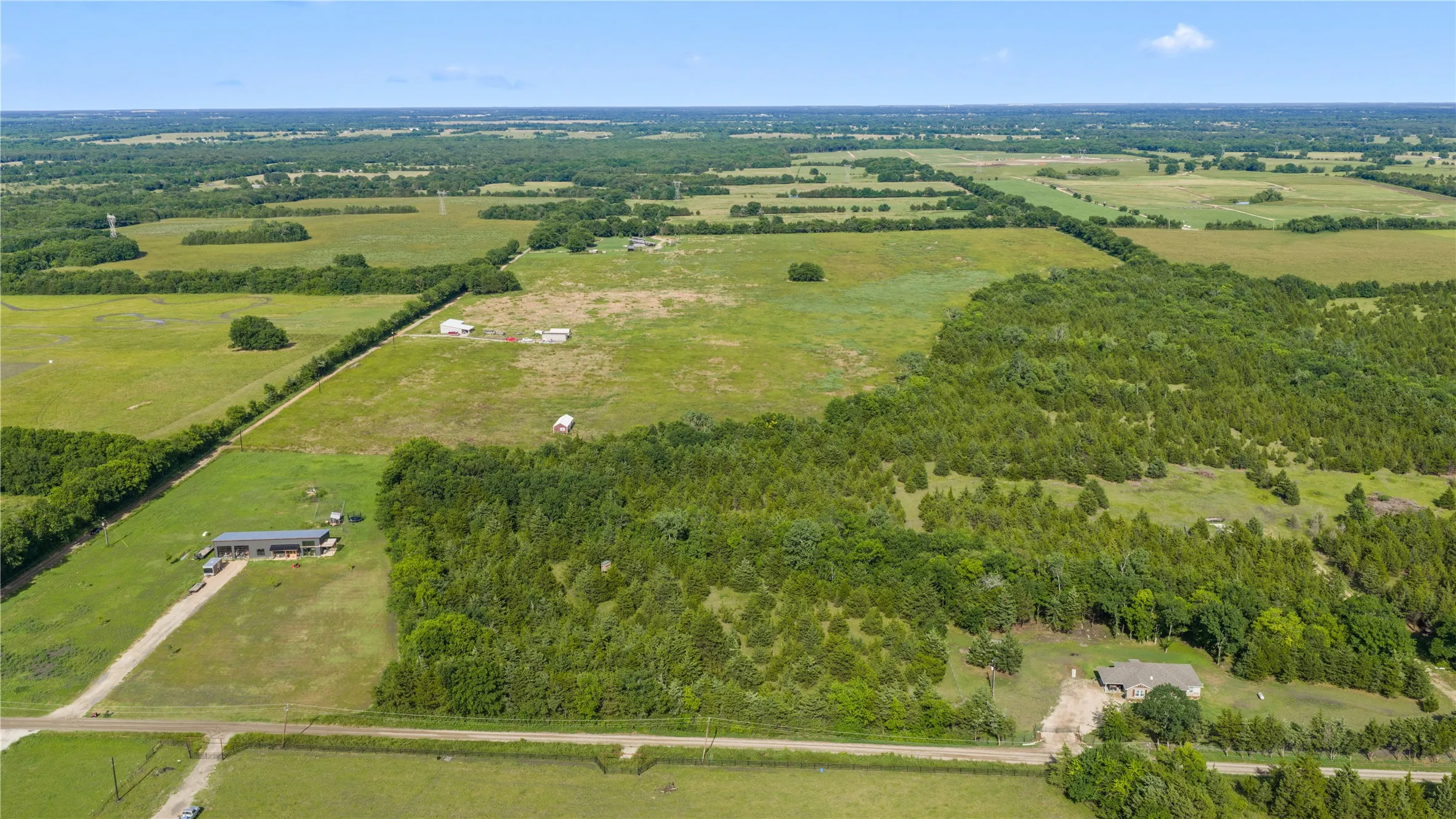 Expansive rural landscape featuring open fields and significant tree coverage