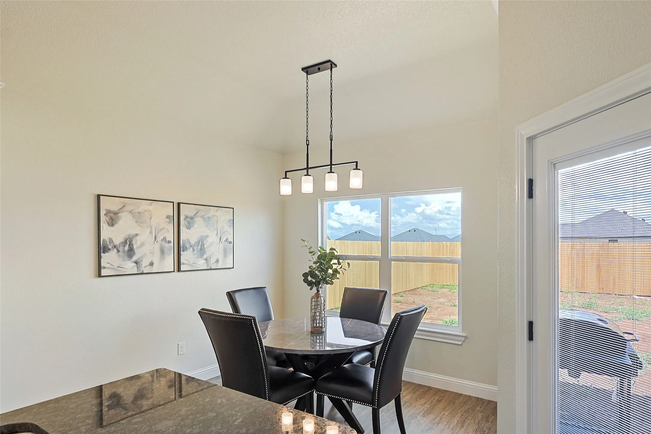 Dining area featuring a contemporary linear chandelier, multiple windows, and light wood-finish flooring
