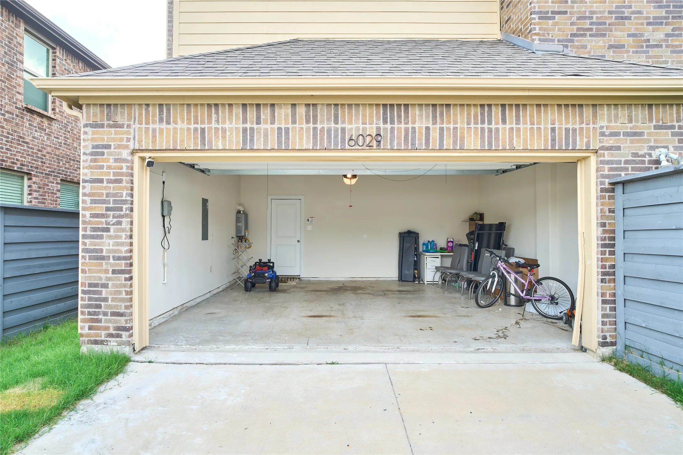 Two-car garage featuring brick and siding exterior, concrete flooring, and an interior access door