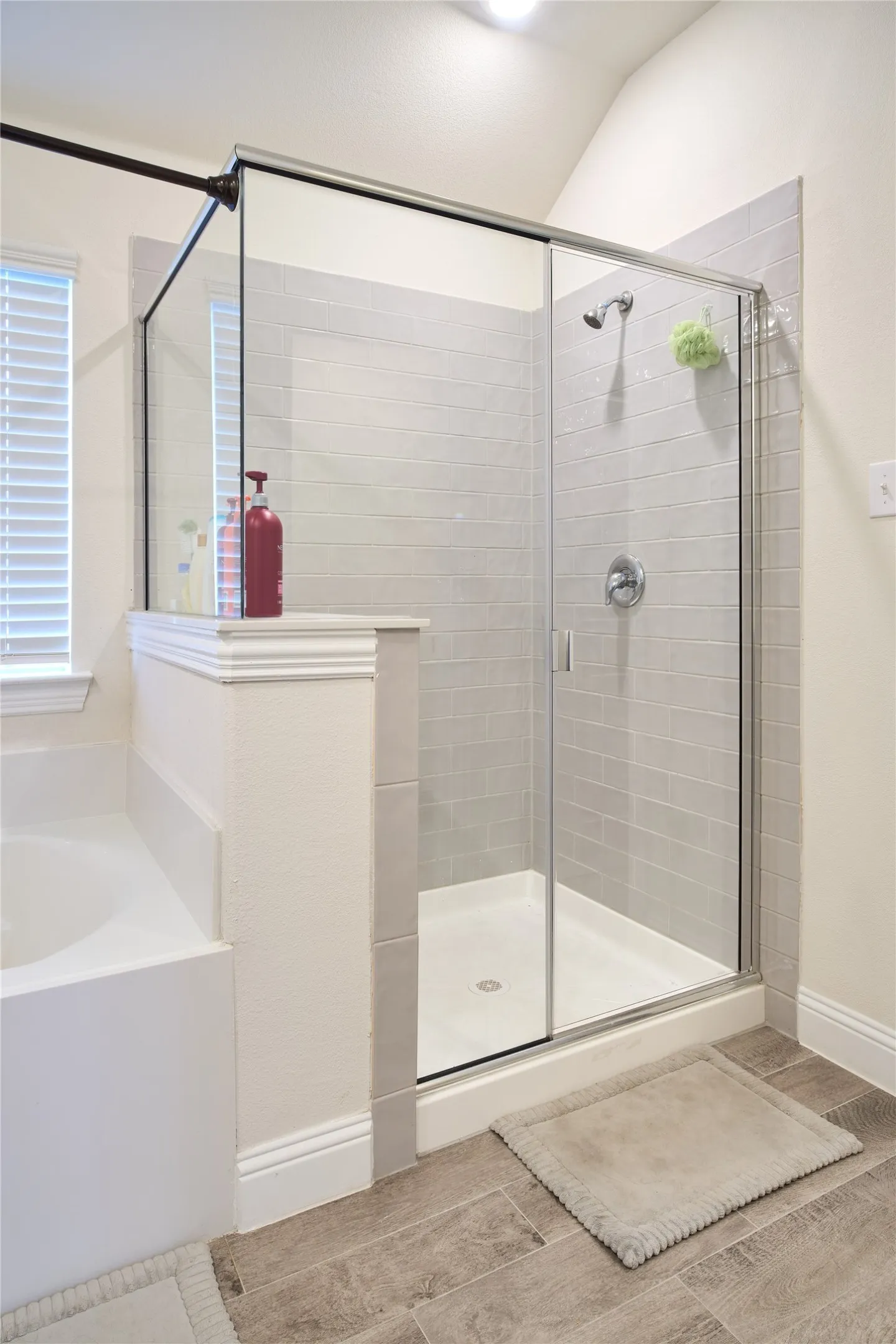 Glass-enclosed shower featuring a tiled surround, chrome fixtures, and a white shower pan