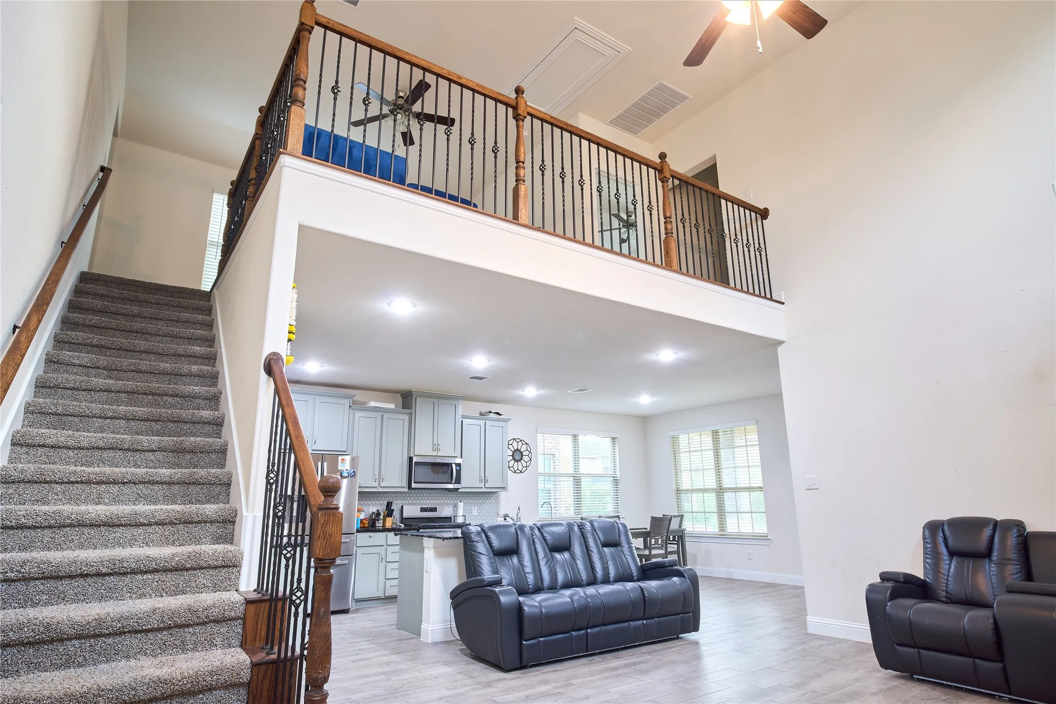 Two-story living area with a loft overhead, featuring a carpeted staircase with wood and wrought iron railings