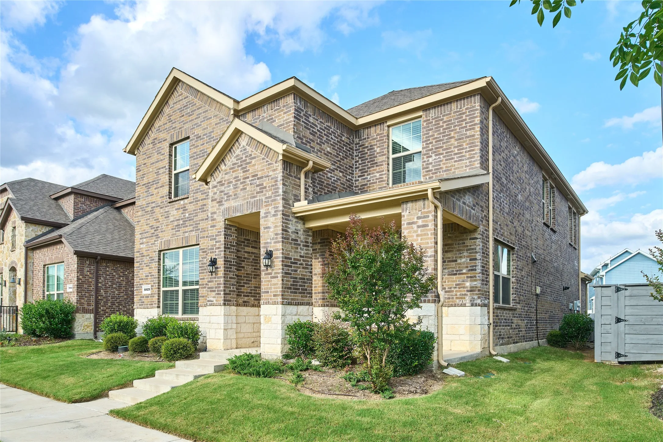 Two-story residence featuring a brick and stone facade, gabled rooflines, and a covered front entry