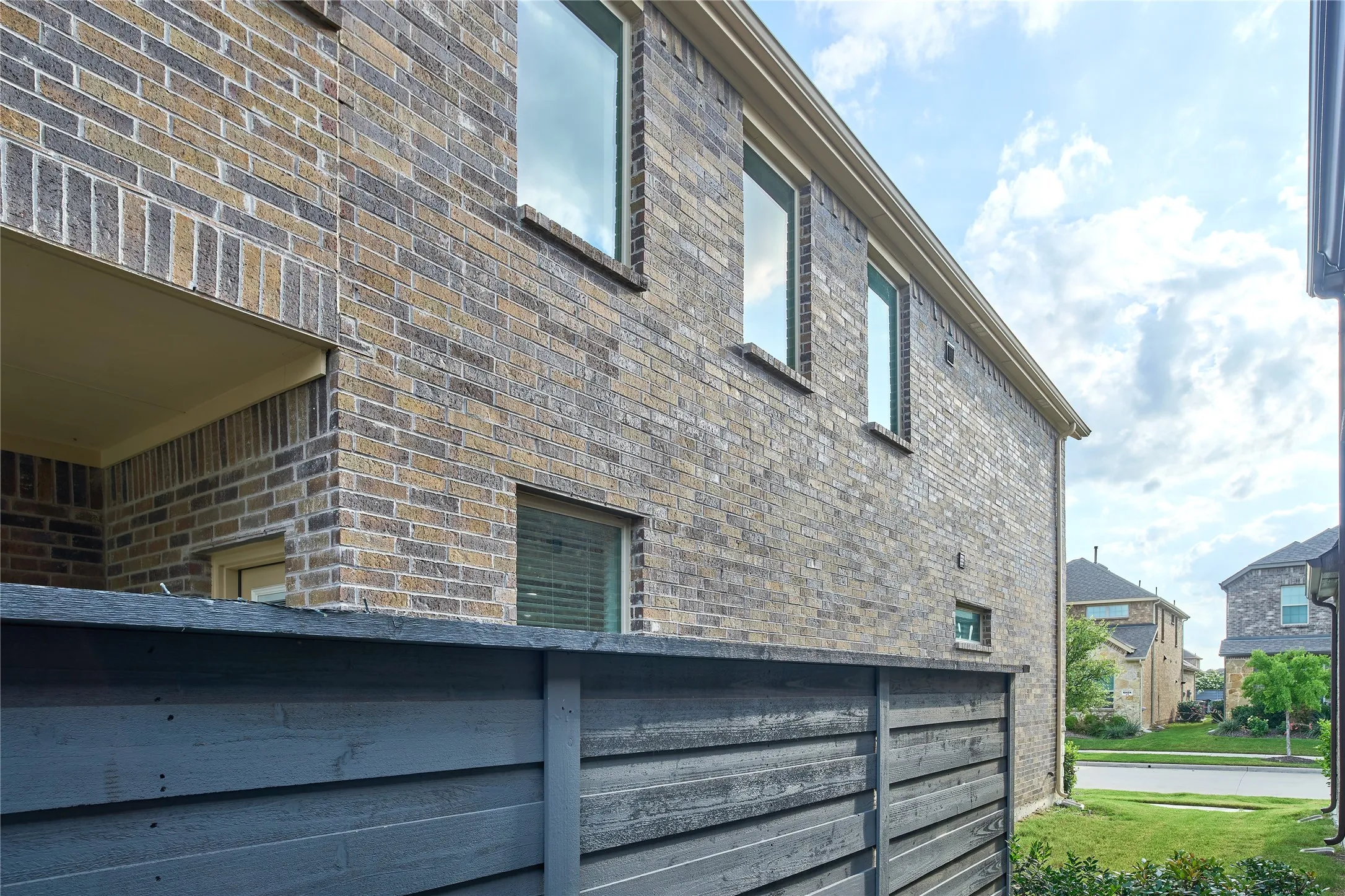 Multi-tone brick exterior featuring multiple windows and a covered outdoor area