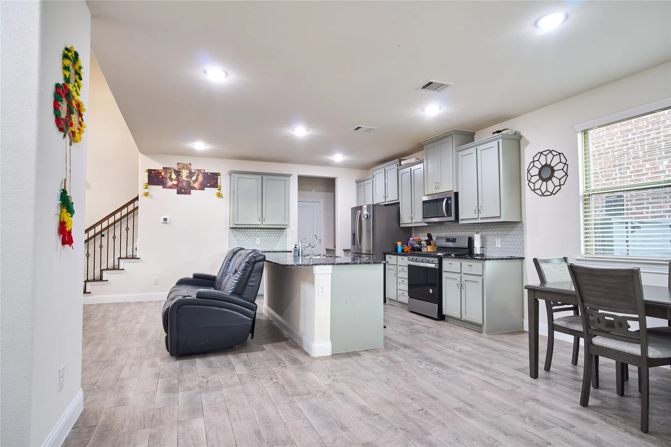 Open-concept kitchen and living area featuring wood-finish flooring, recessed lighting, and a staircase with wrought iron​​‌​​​​‌​​‌‌​‌‌​​​‌‌​‌​‌​‌​​​‌​​ balusters
