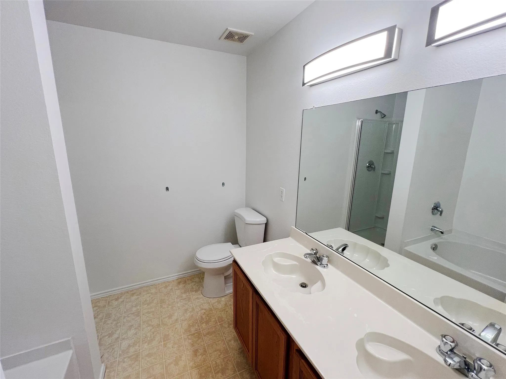Bathroom featuring a dual vanity with integrated sinks and chrome fixtures, ample counter space, a large mirror, and overhead strip lighting