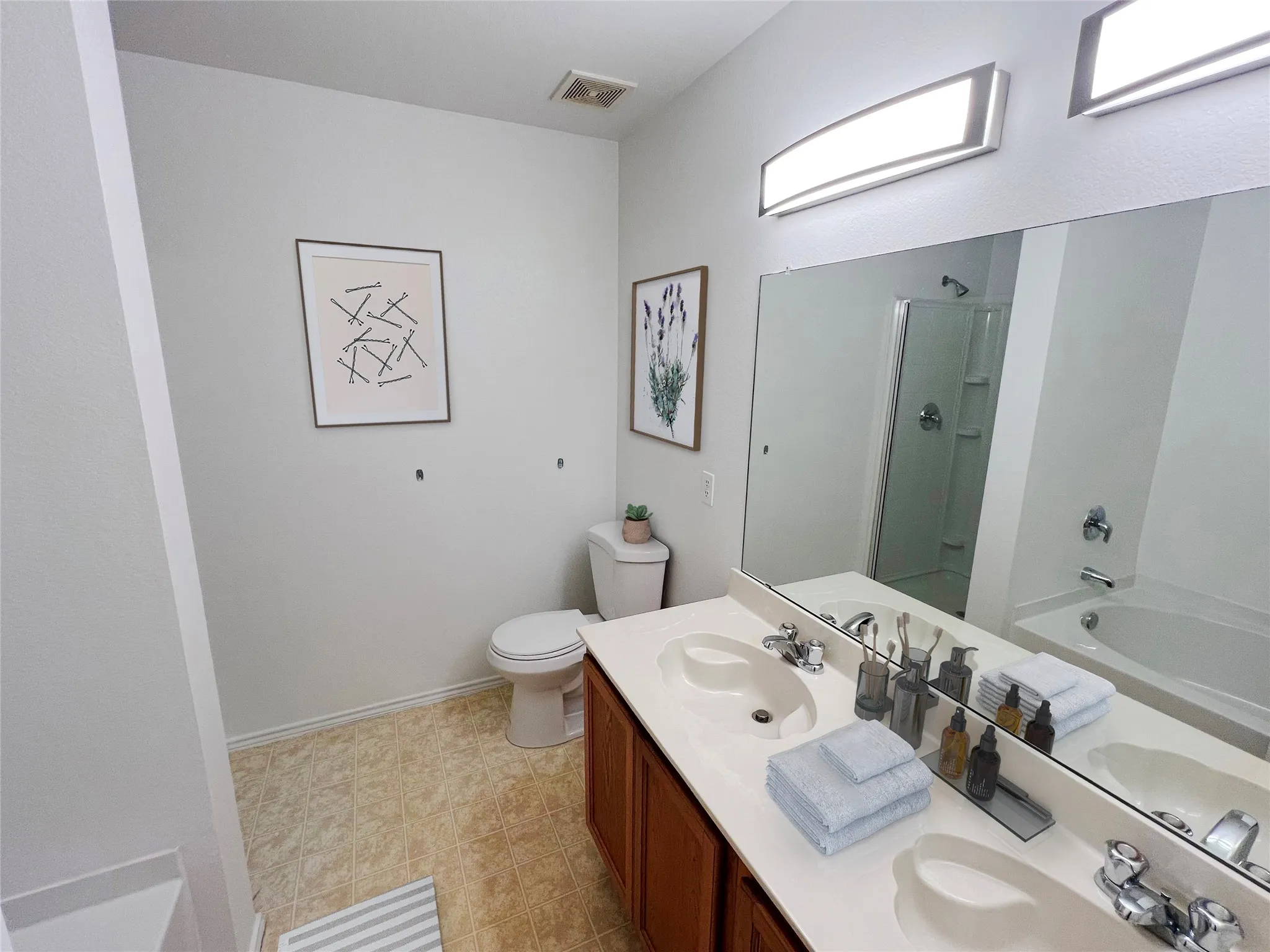 Bathroom featuring a dual vanity with integrated sinks, a large mirror, and overhead linear lighting