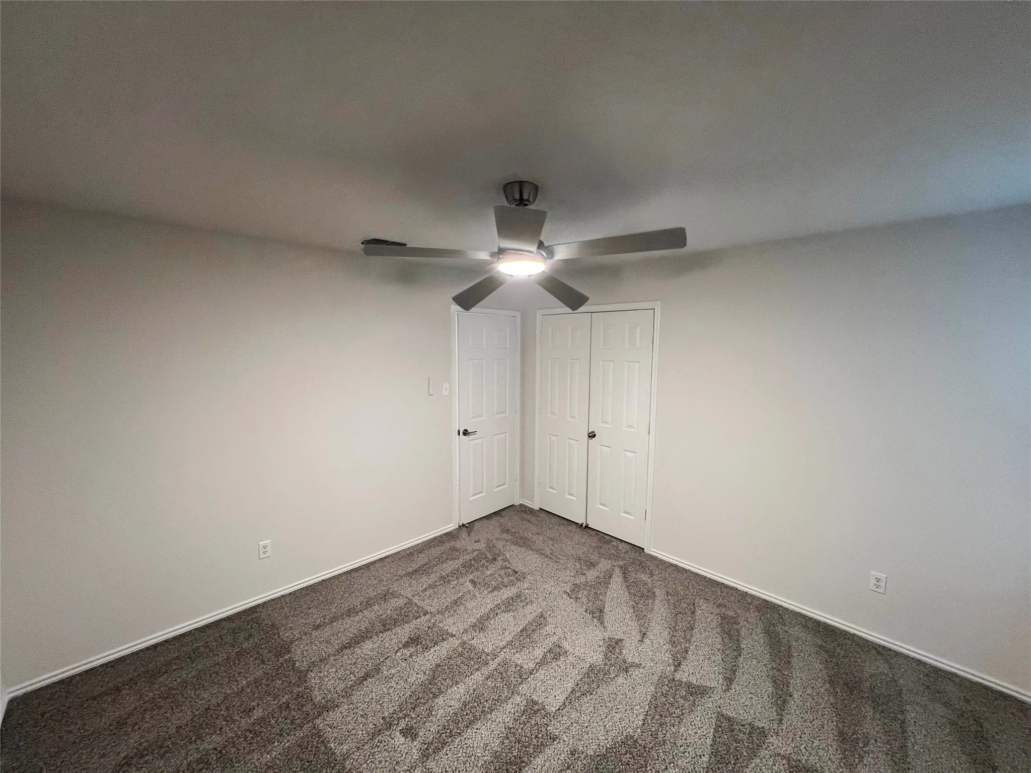 Neutral walls with a contemporary ceiling fan, patterned carpet, and white trim