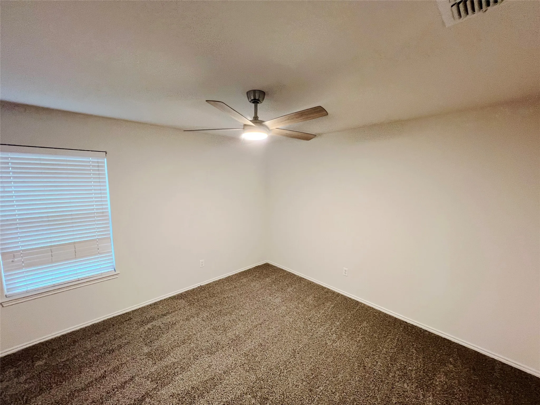 Neutral-toned walls complement the textured brown carpeting