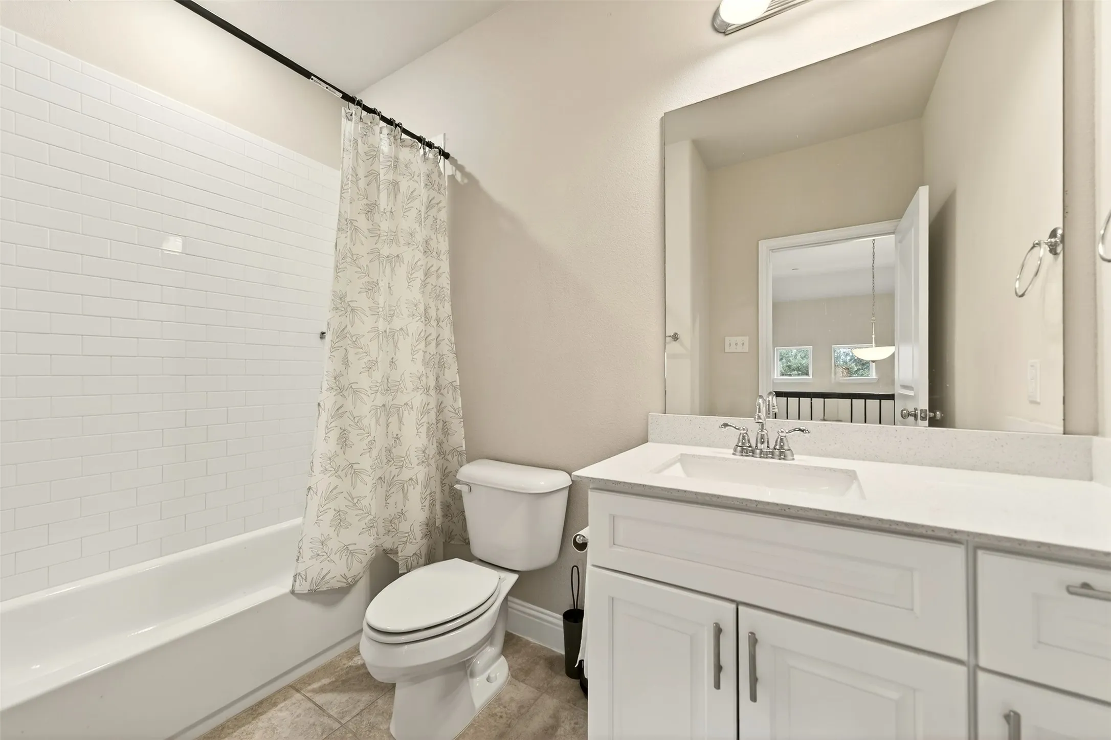 Bathroom featuring a white subway tile tub surround, a toilet, and a vanity with a white countertop and integrated sink