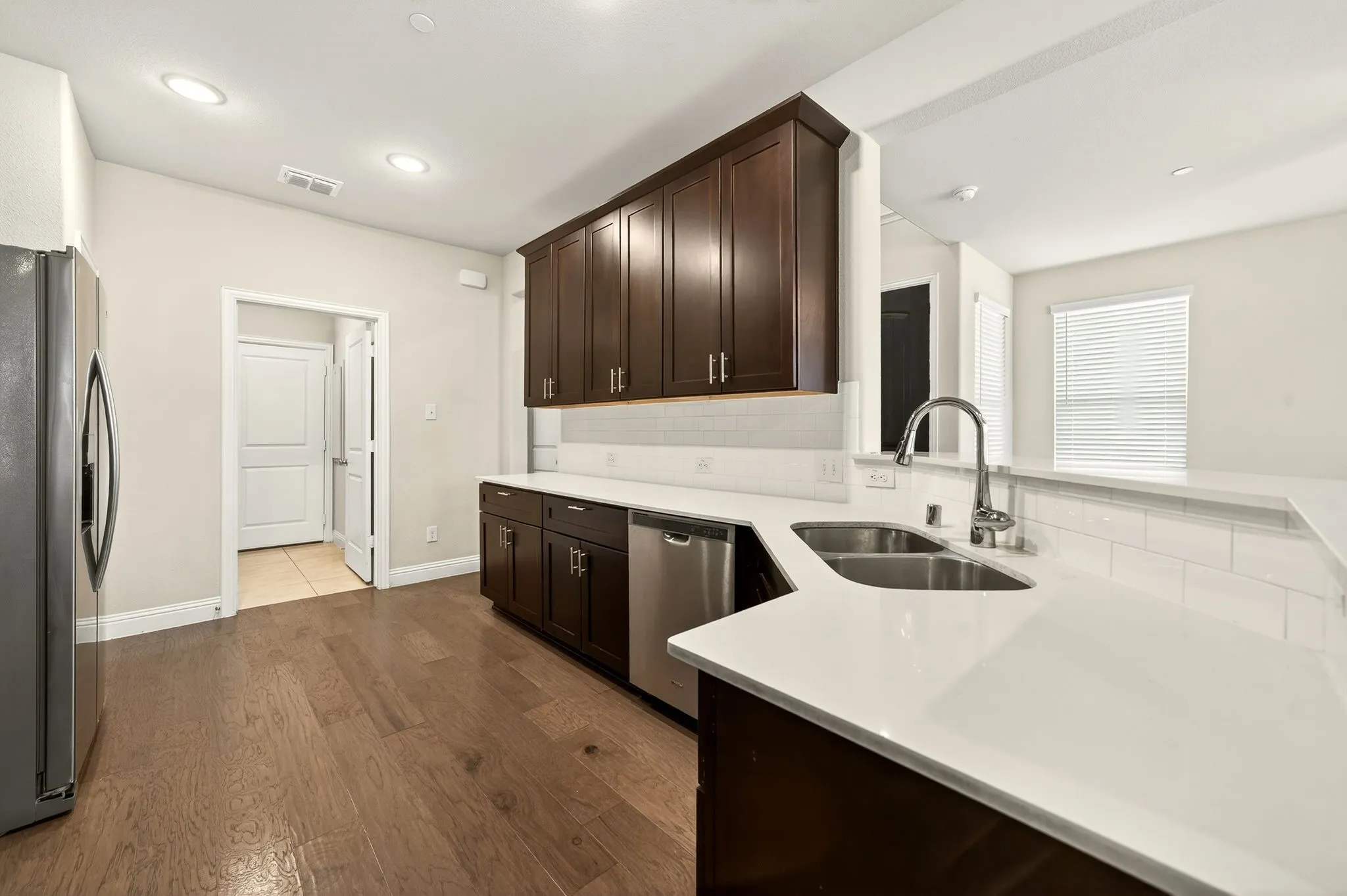 Modern kitchen featuring dark wood cabinetry, white countertops, and stainless steel appliances