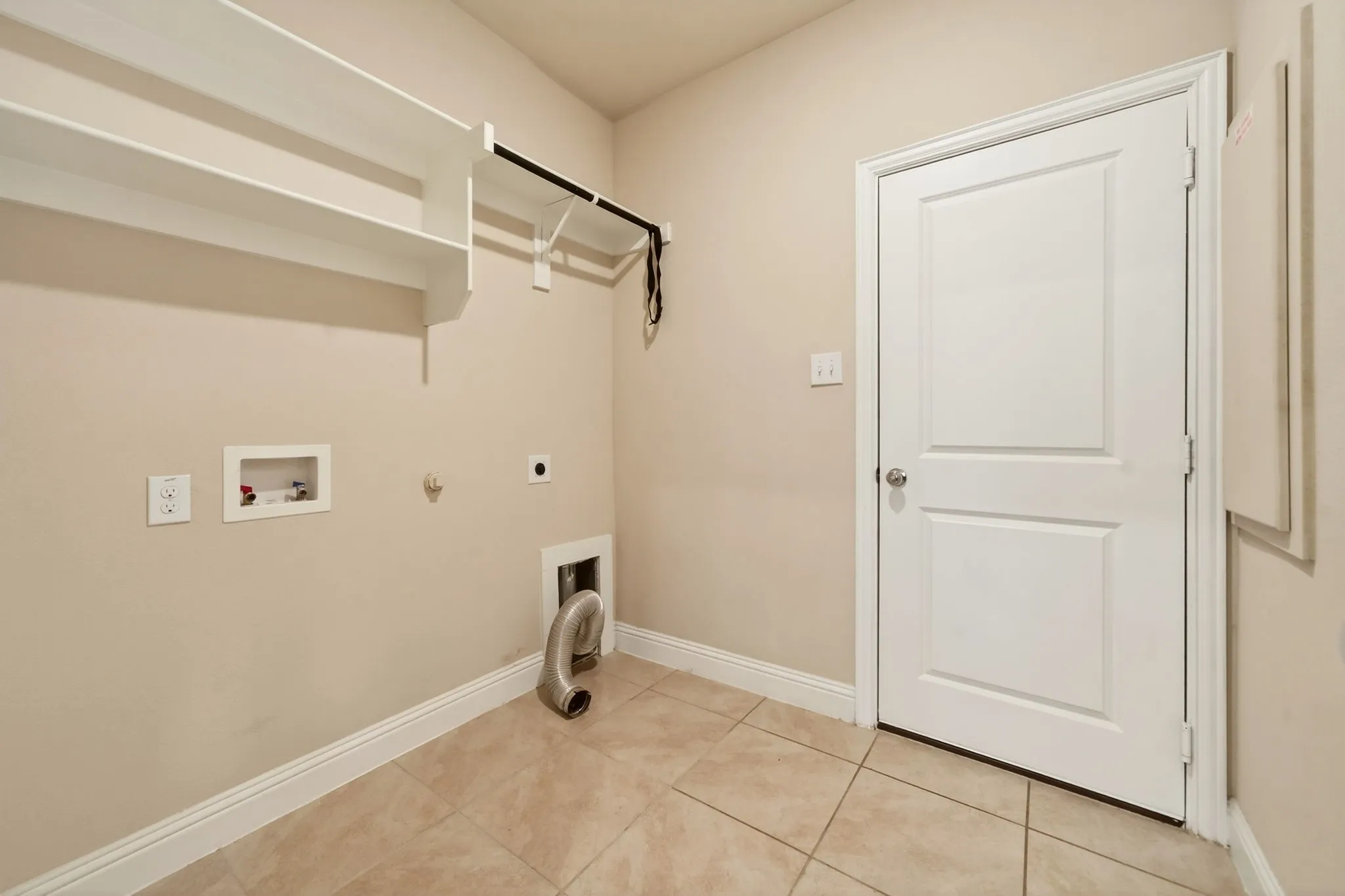 Laundry room with tiled flooring, neutral wall paint, and white baseboards
