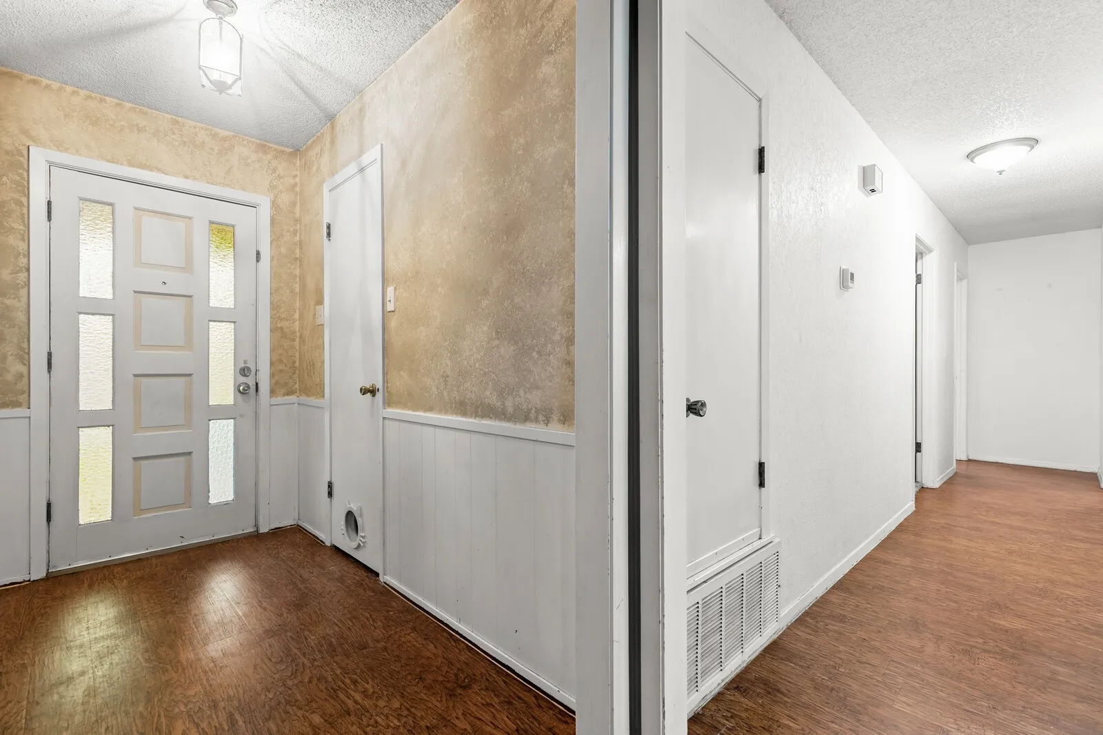 Entryway with wood-finish flooring, white paneled wainscoting, and a white front door featuring multiple frosted glass inserts
