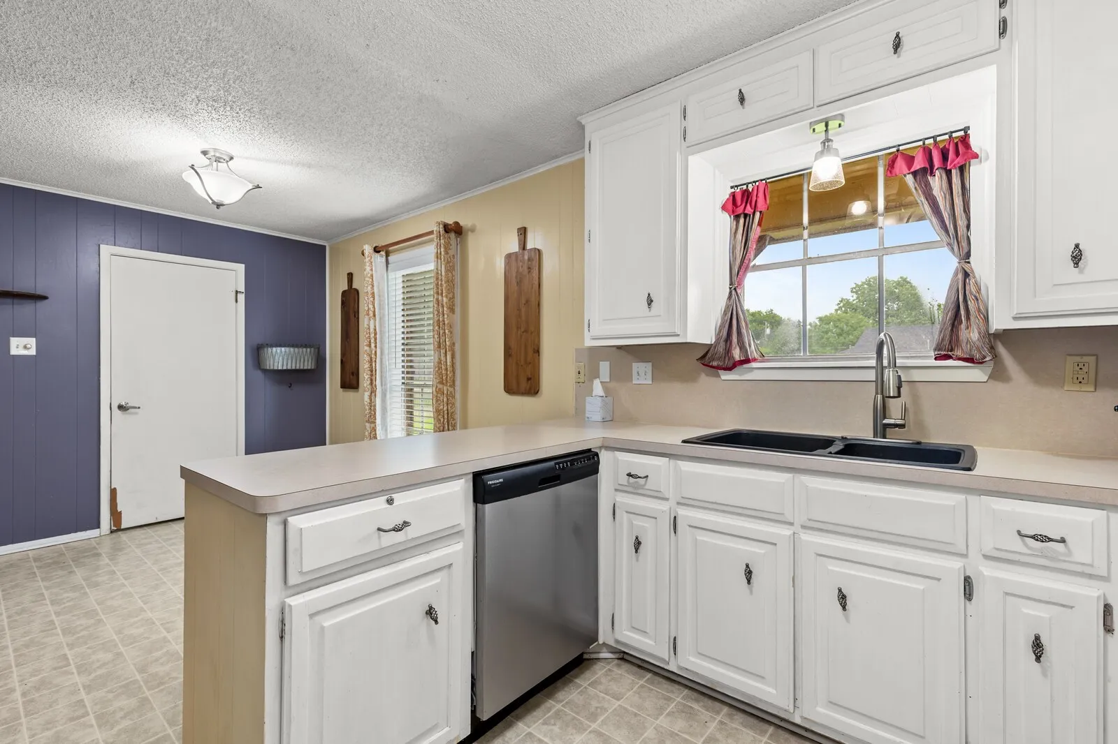 Kitchen featuring white cabinetry, light-toned countertops, and a double basin sink with a gooseneck faucet
