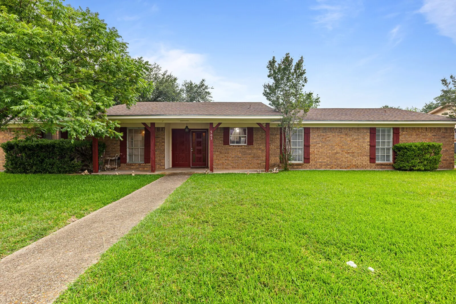 Brick exterior with a covered entryway, red shutters, and a concrete walkway