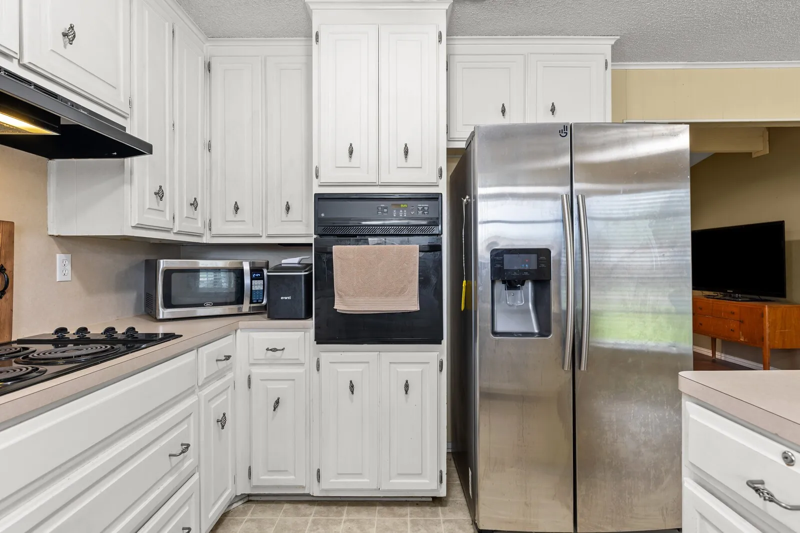 Kitchen featuring white cabinetry with dark hardware, a built-in oven, and a stainless-steel side-by-side refrigerator