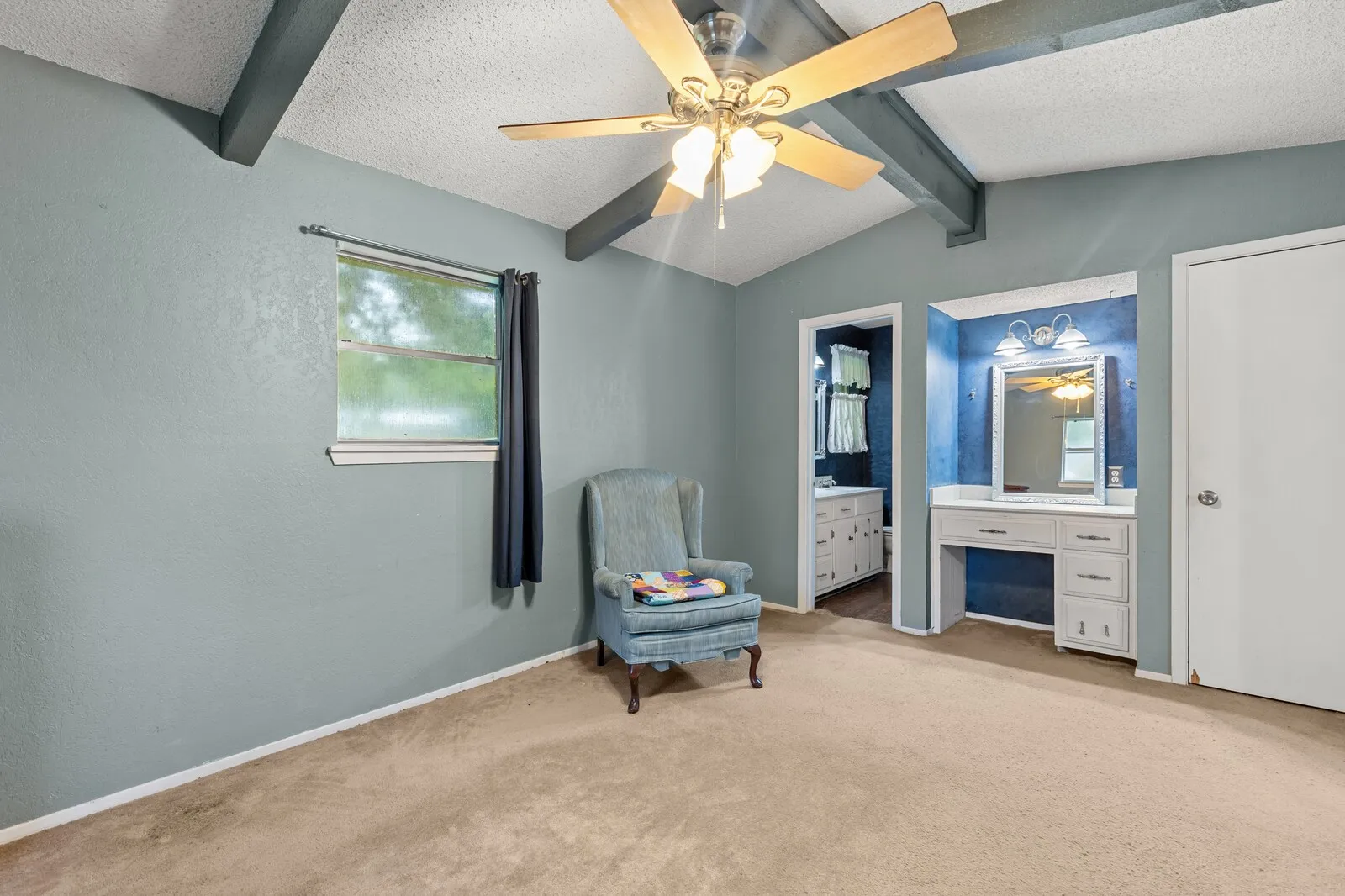 Room featuring a vaulted ceiling with exposed beams, a ceiling fan, and carpeted flooring