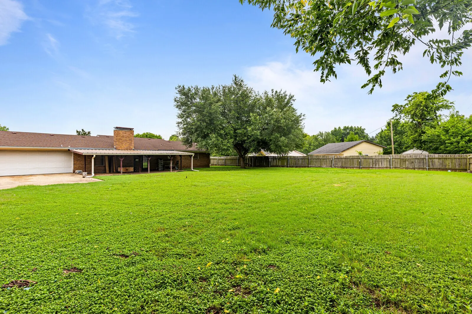 Spacious backyard featuring an expansive lawn and mature trees