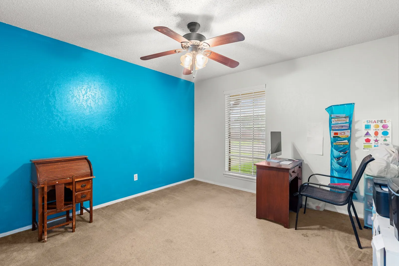 Carpeted room featuring a ceiling fan with light fixture, a window with blinds, and white baseboards