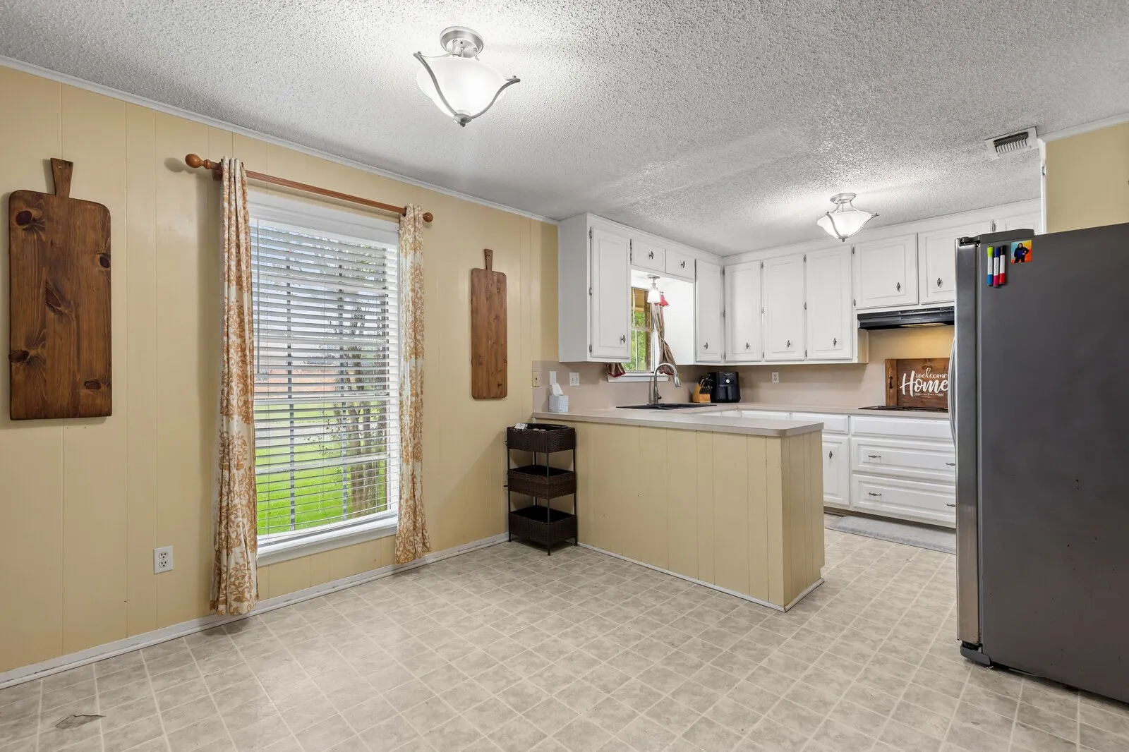 Kitchen featuring white cabinetry, light-toned countertops, and an integrated sink with a window above