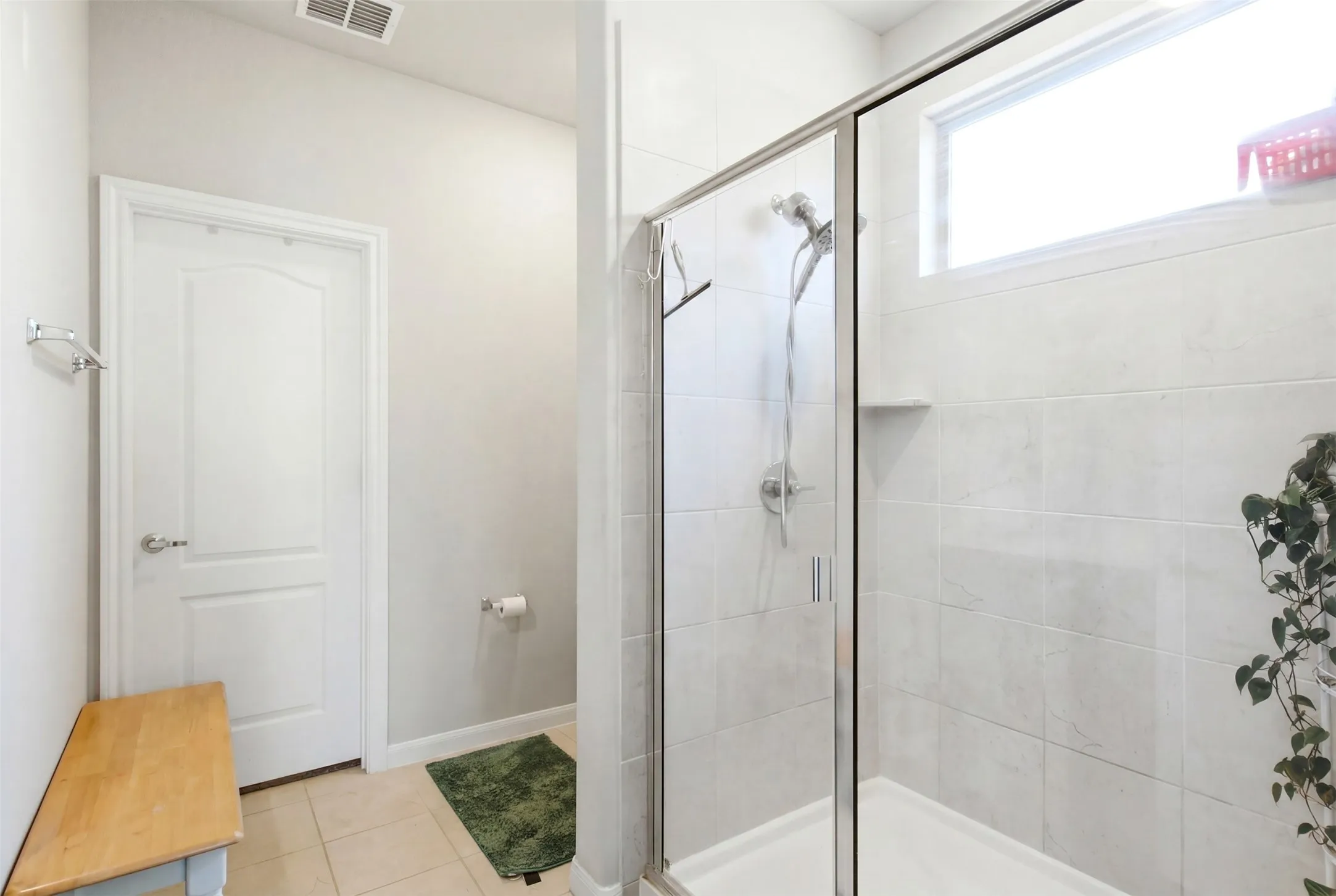 Walk-in shower with clear glass enclosure and light-toned tile surround