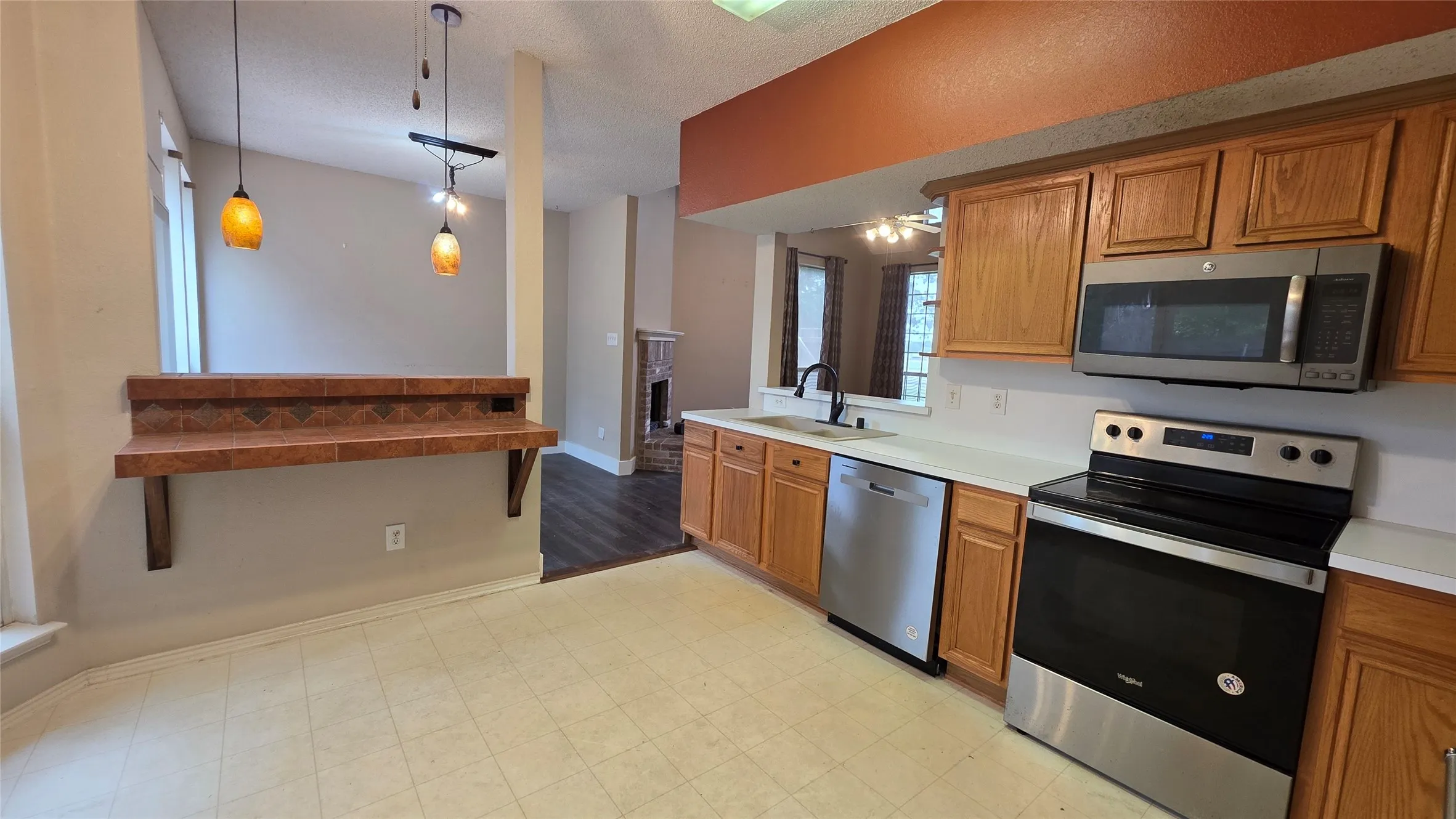 Kitchen featuring wood cabinetry, white countertops, and stainless steel appliances, including an oven, microwave, and dishwasher