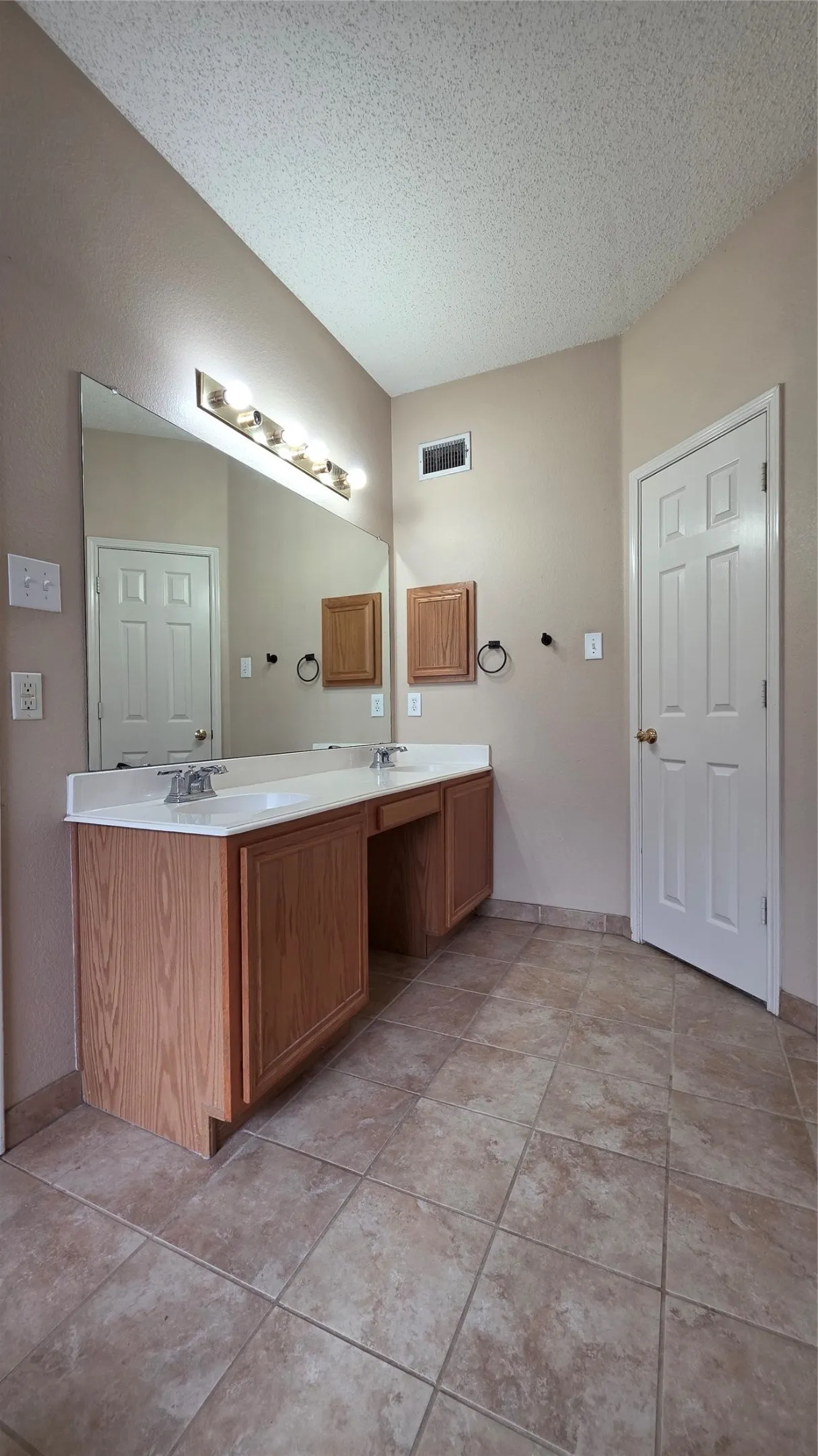 Bathroom featuring a double vanity with wood-finish cabinetry, white countertop, and dual sinks