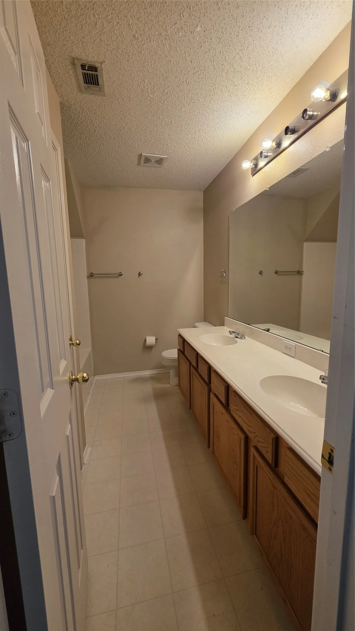 Bathroom featuring a double vanity with integrated sinks, wood-finish cabinetry, and a full-width mirror