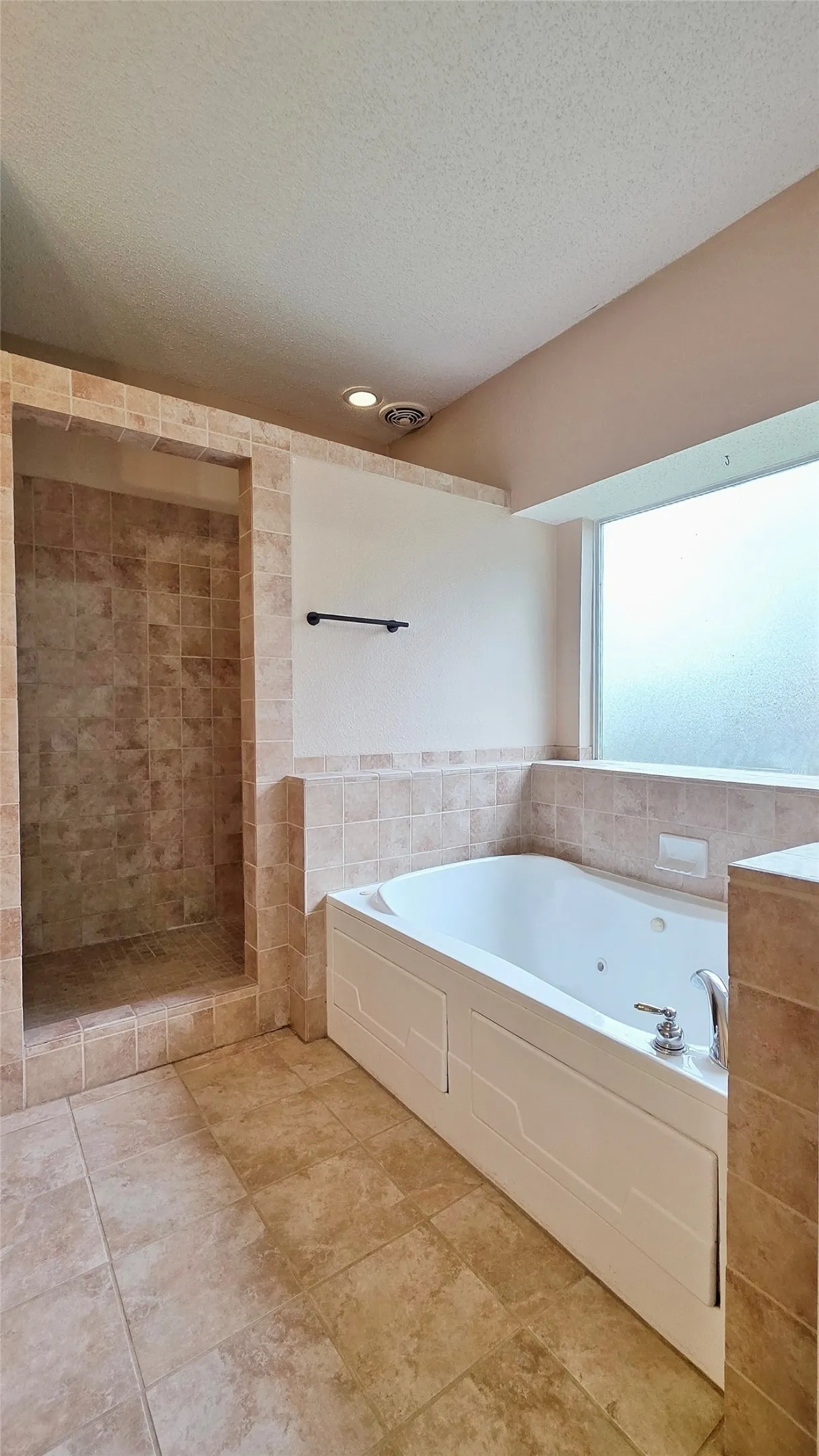 Tiled walk-in shower with a built-in bench, accompanied by a jetted tub