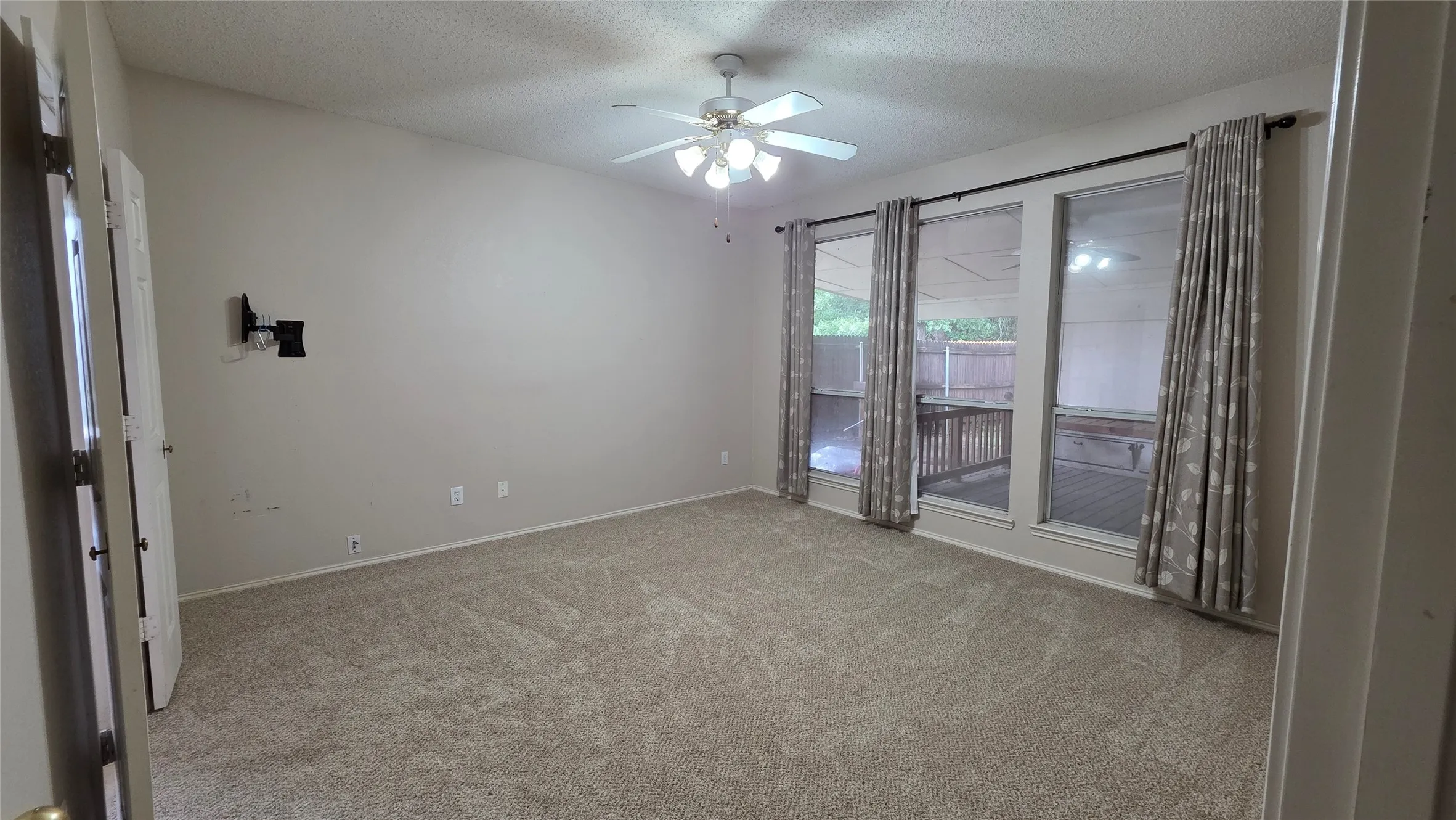 Carpeted room featuring a ceiling fan with integrated lighting, multiple windows, and a dedicated wall mount