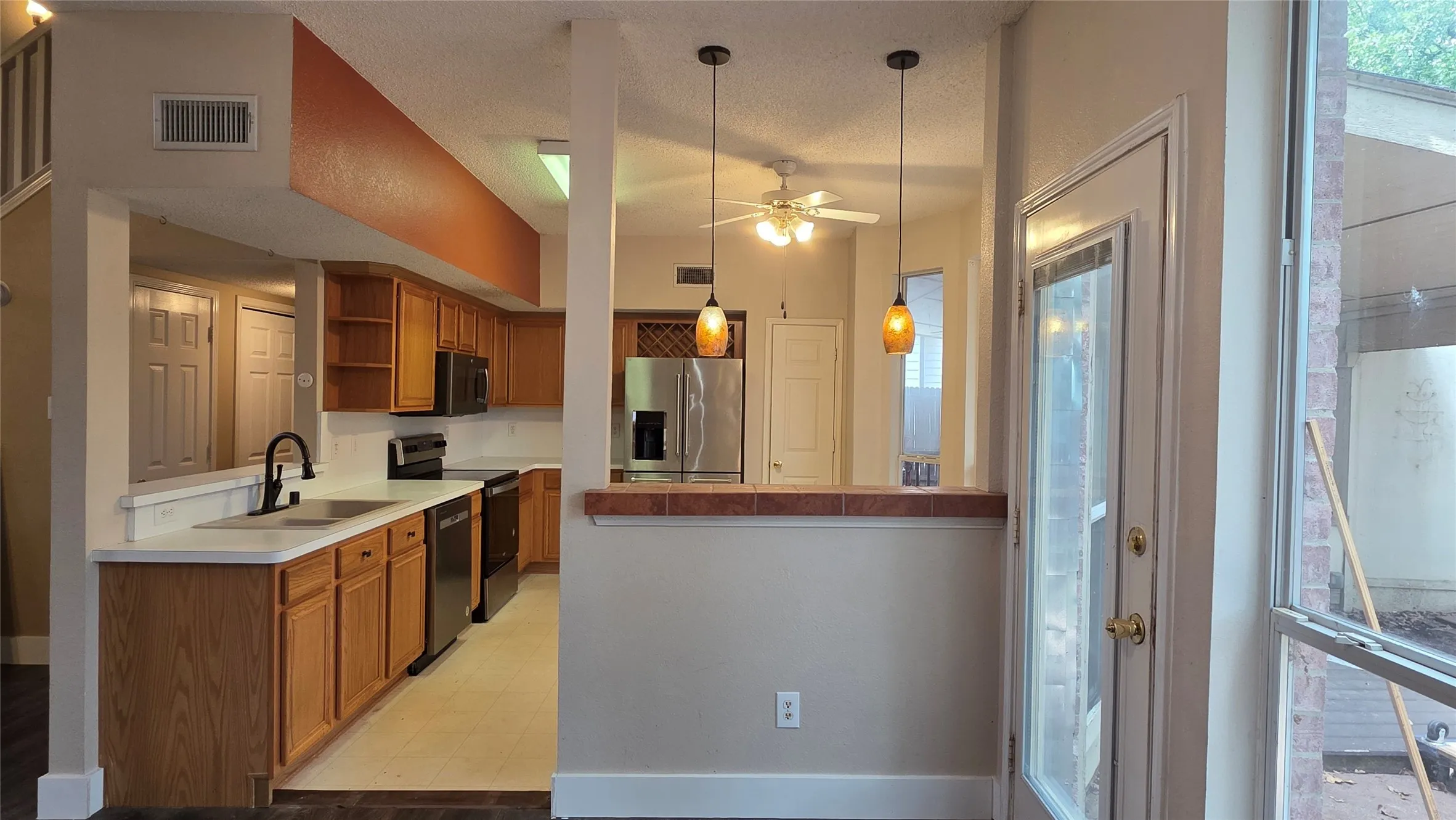 Kitchen featuring wood cabinetry, white countertops, a matte black faucet, and black appliances