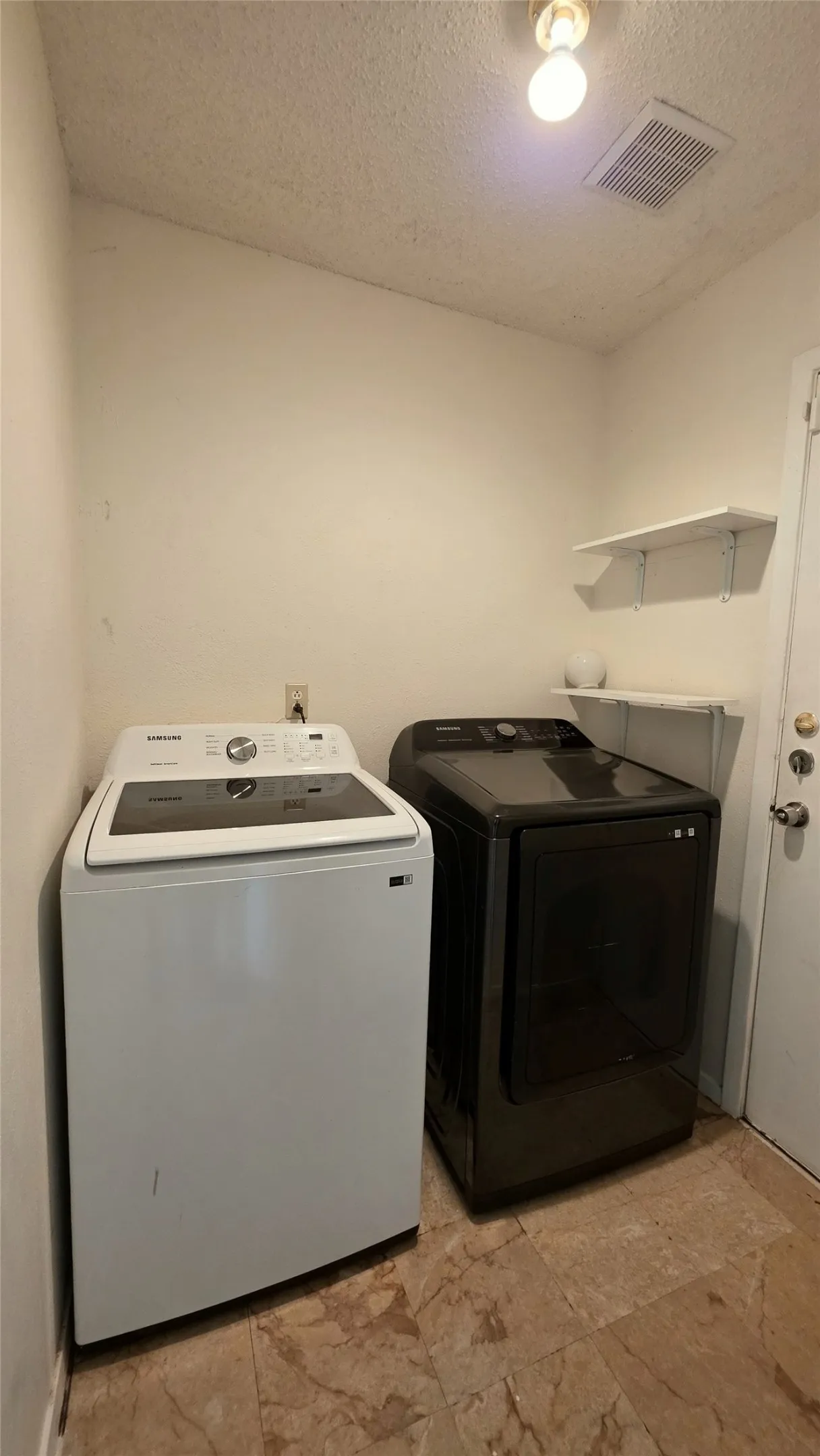 Dedicated laundry space featuring a tiled floor, white walls, and built-in shelving