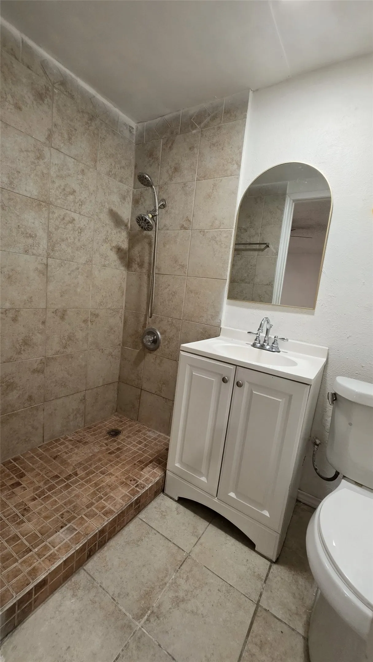 Tiled shower enclosure with a mosaic tile base, featuring a chrome shower fixture