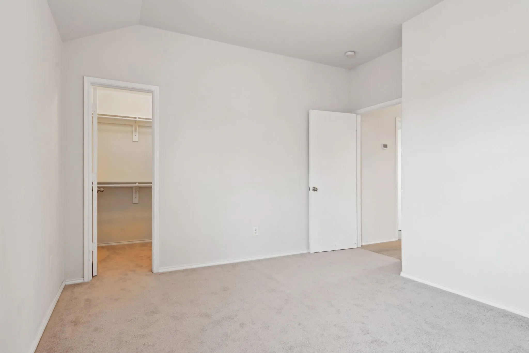 Unfurnished bedroom with vaulted ceiling, a spacious closet, light carpet