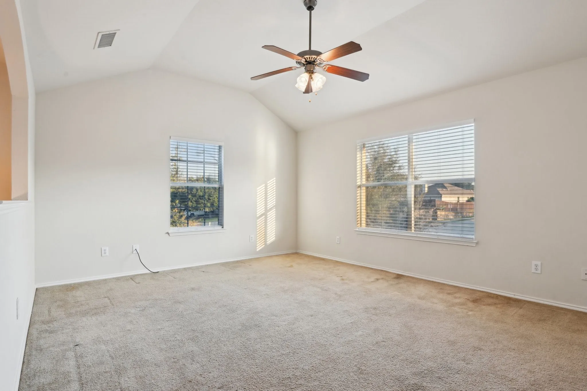 room featuring vaulted ceiling, light carpet, and ceiling fan