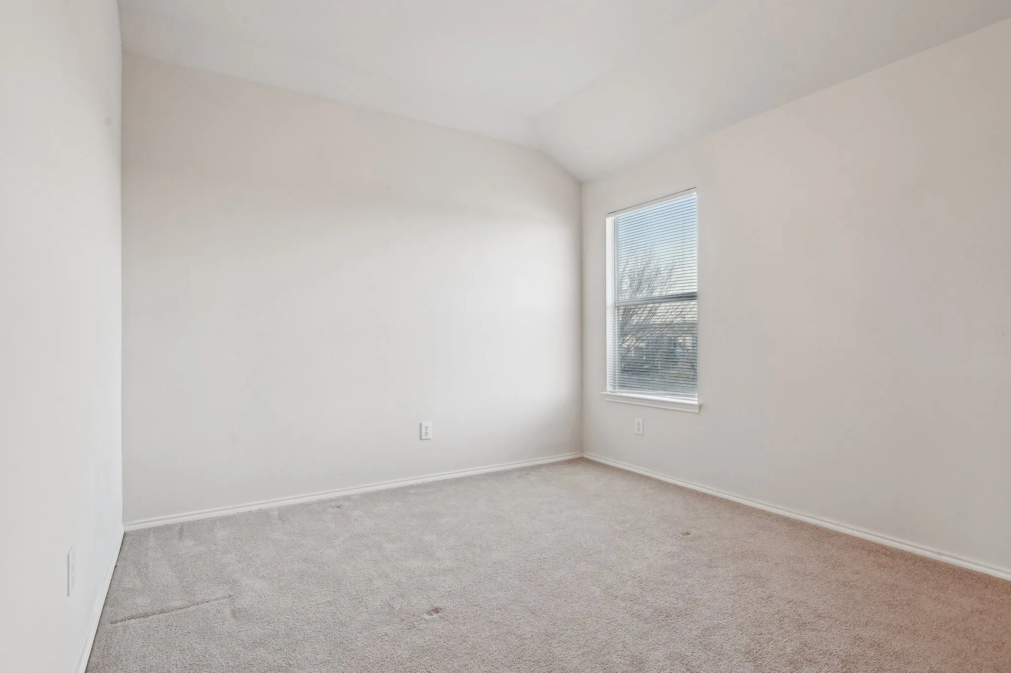 Carpeted empty room featuring lofted ceiling