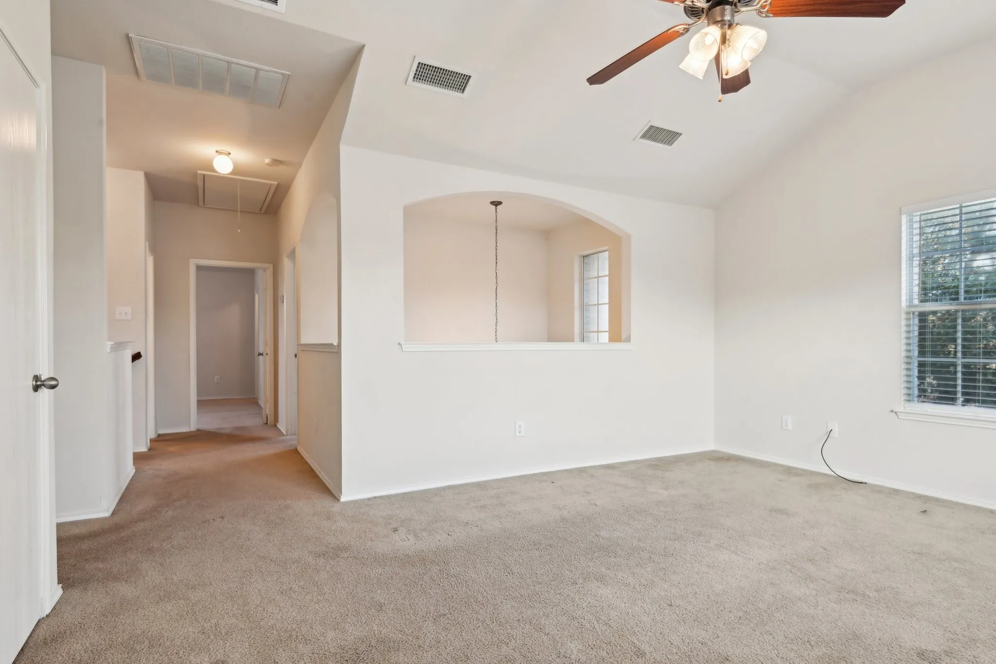 Carpeted spare room featuring lofted ceiling and ceiling fan