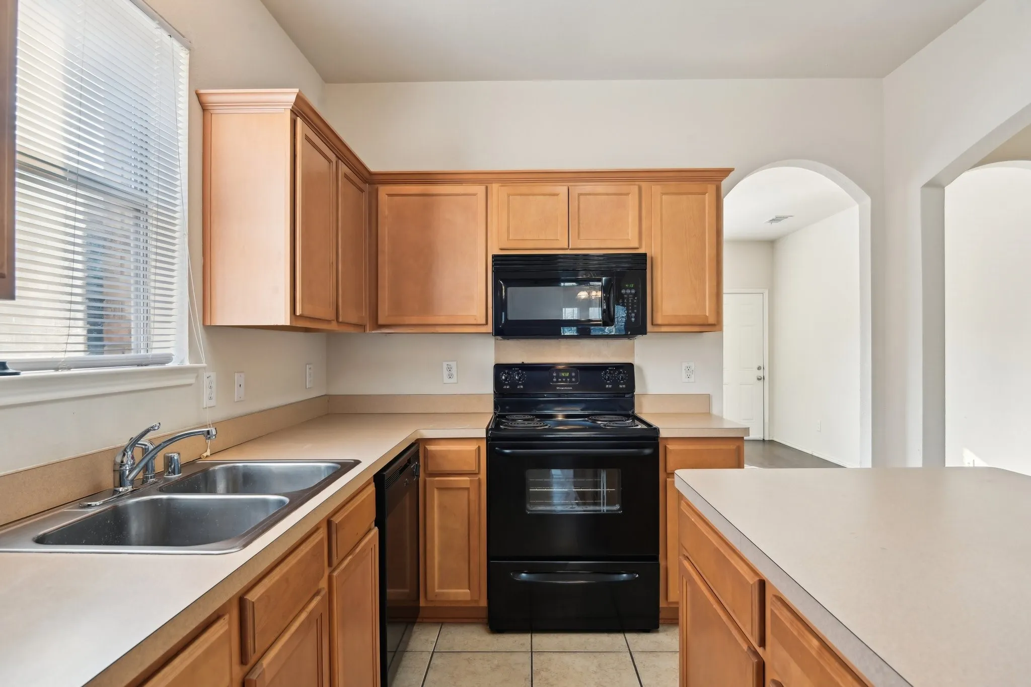 Kitchen featuring sink, light tile patterned floors, and black appliances