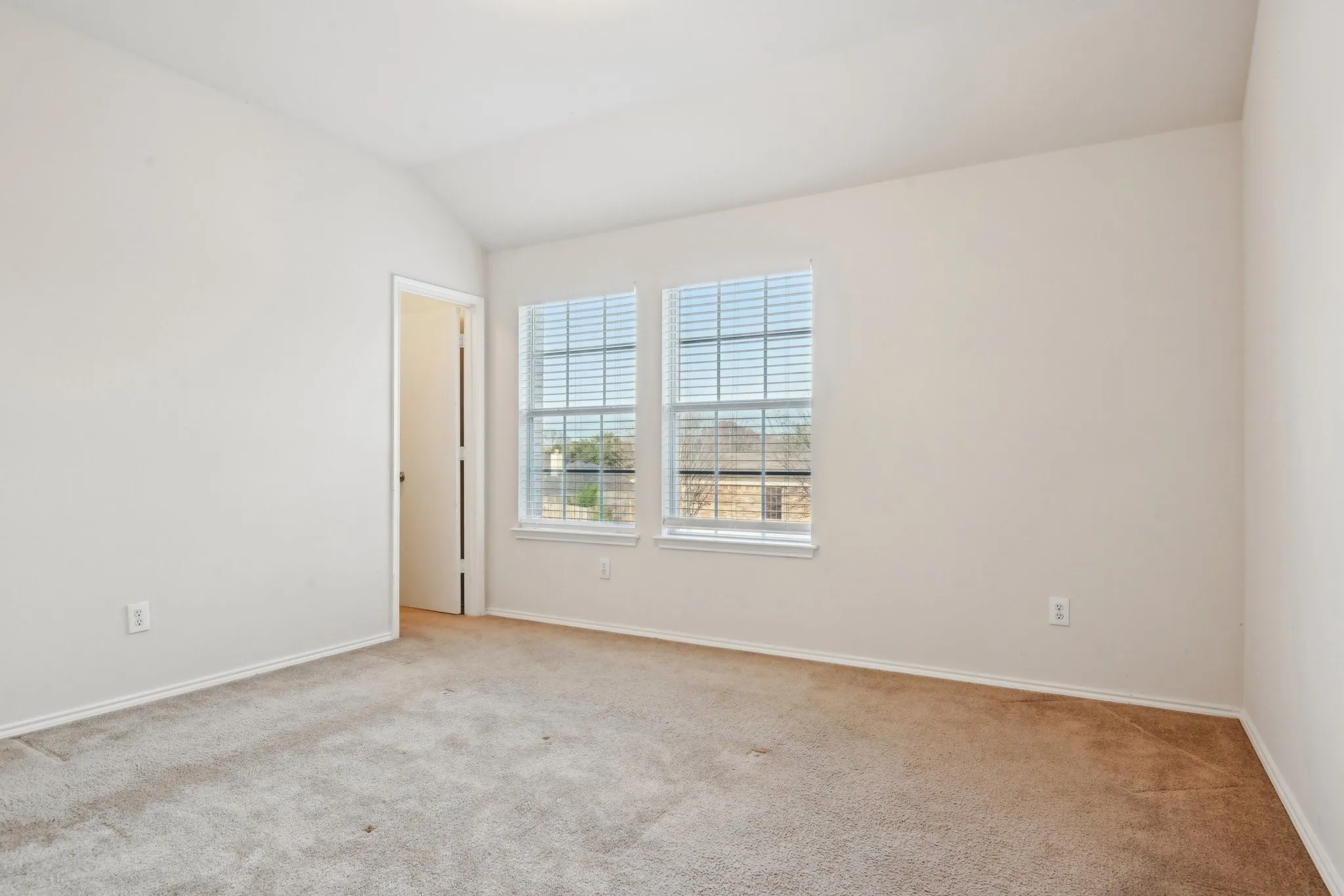 Carpeted spare room featuring lofted ceiling